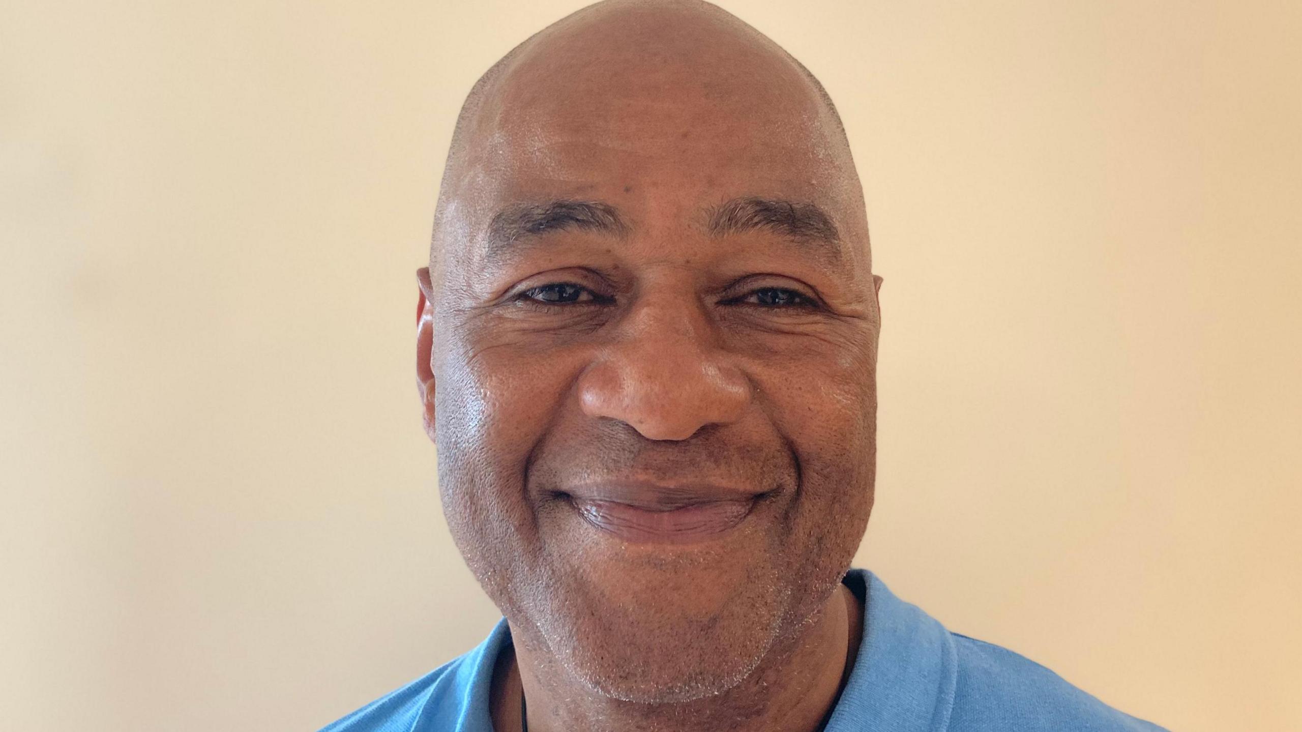 A man in a blue polo shirt smiles at the camera.