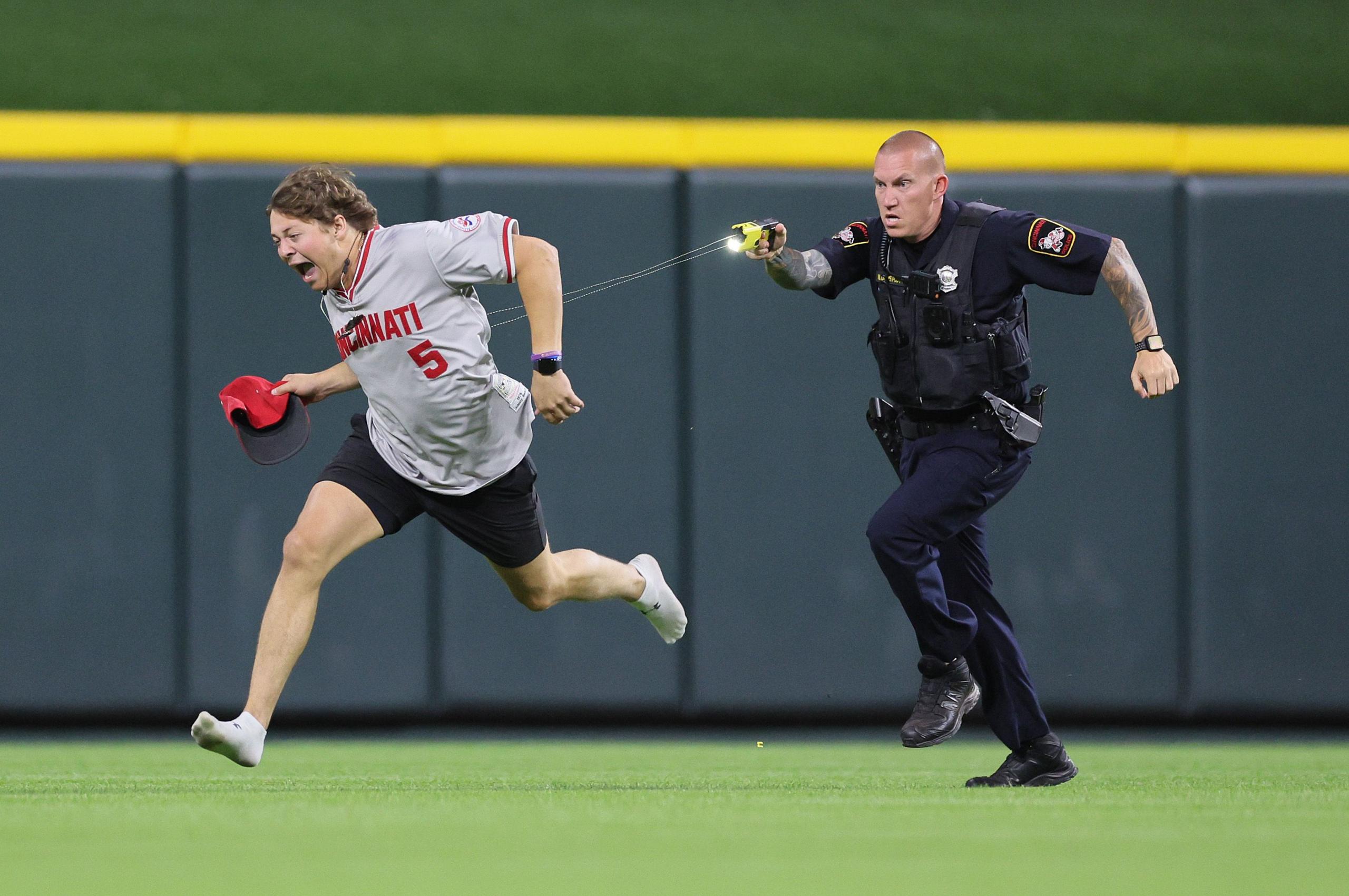 A fan is Tasered by a police officer as he runs on the field during the MLB game between Cincinnati Reds and Cleveland Guardians at Great American Ball Park in Cincinnati