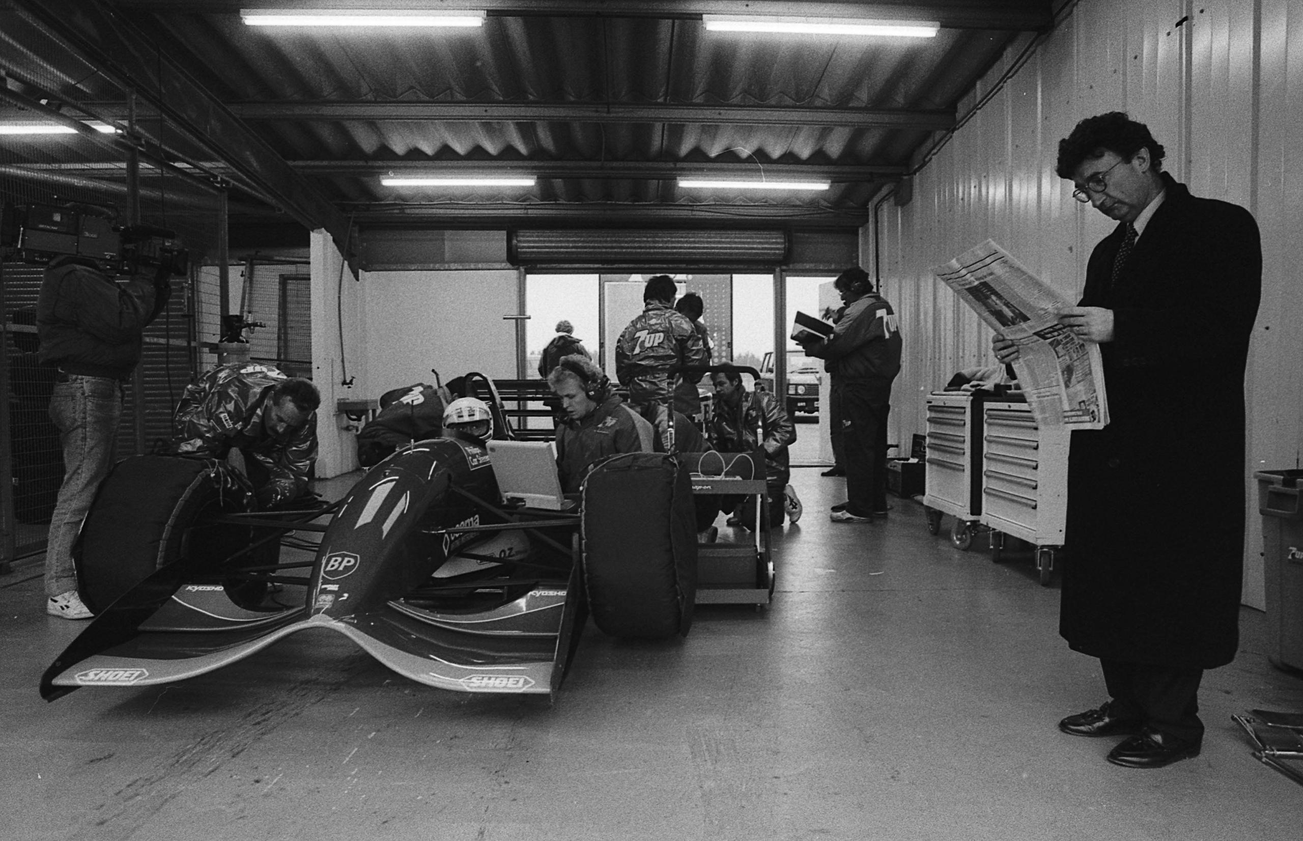 Eddie Jordan reading the Newspaper beside his Formula 1 car