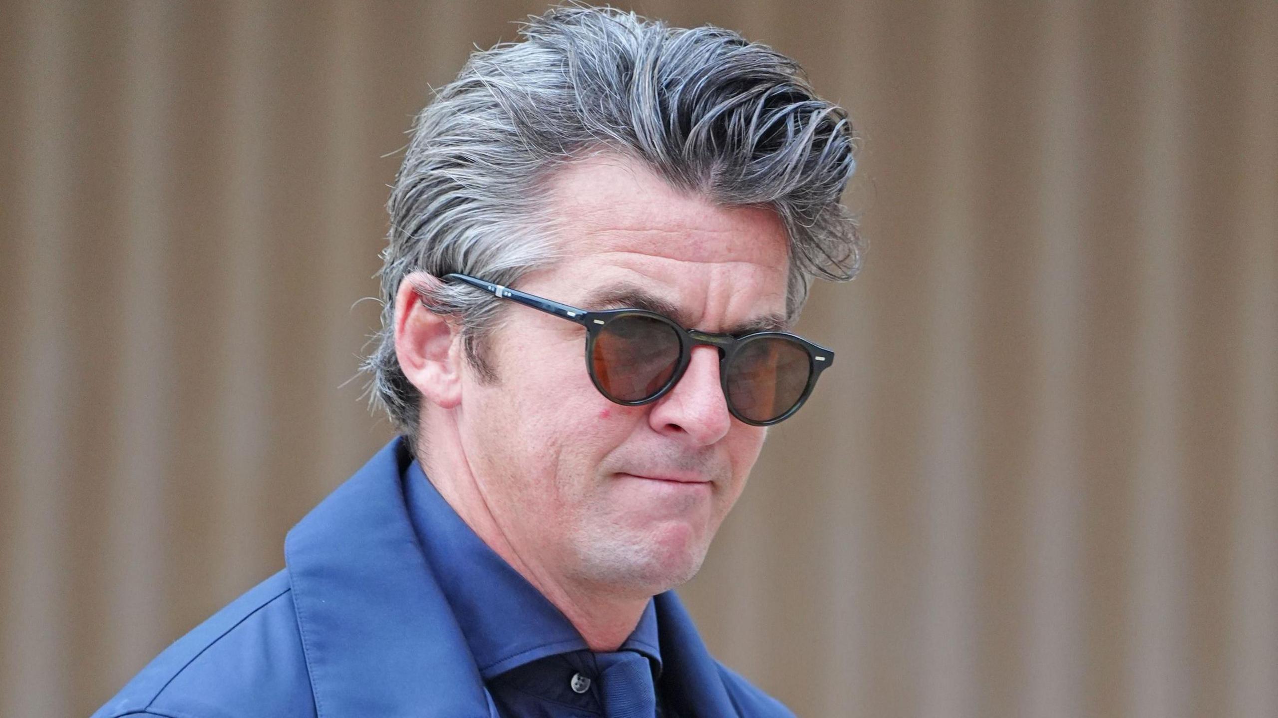 Joey Barton arriving at court wearing navy suit and jacket