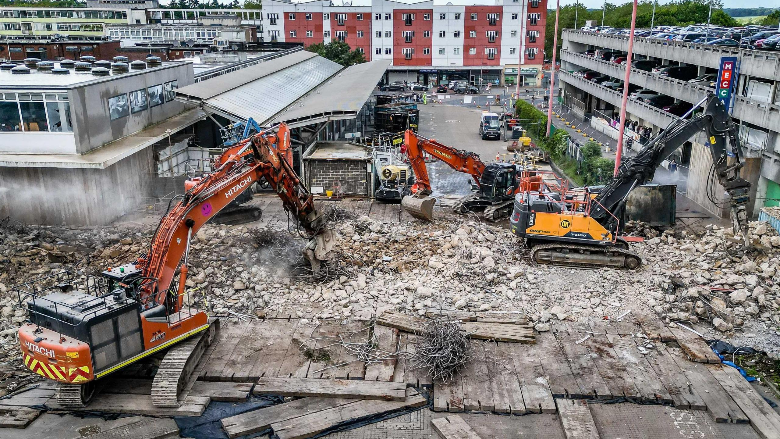 Bright orange specialist demolition equipment ripping down walkway