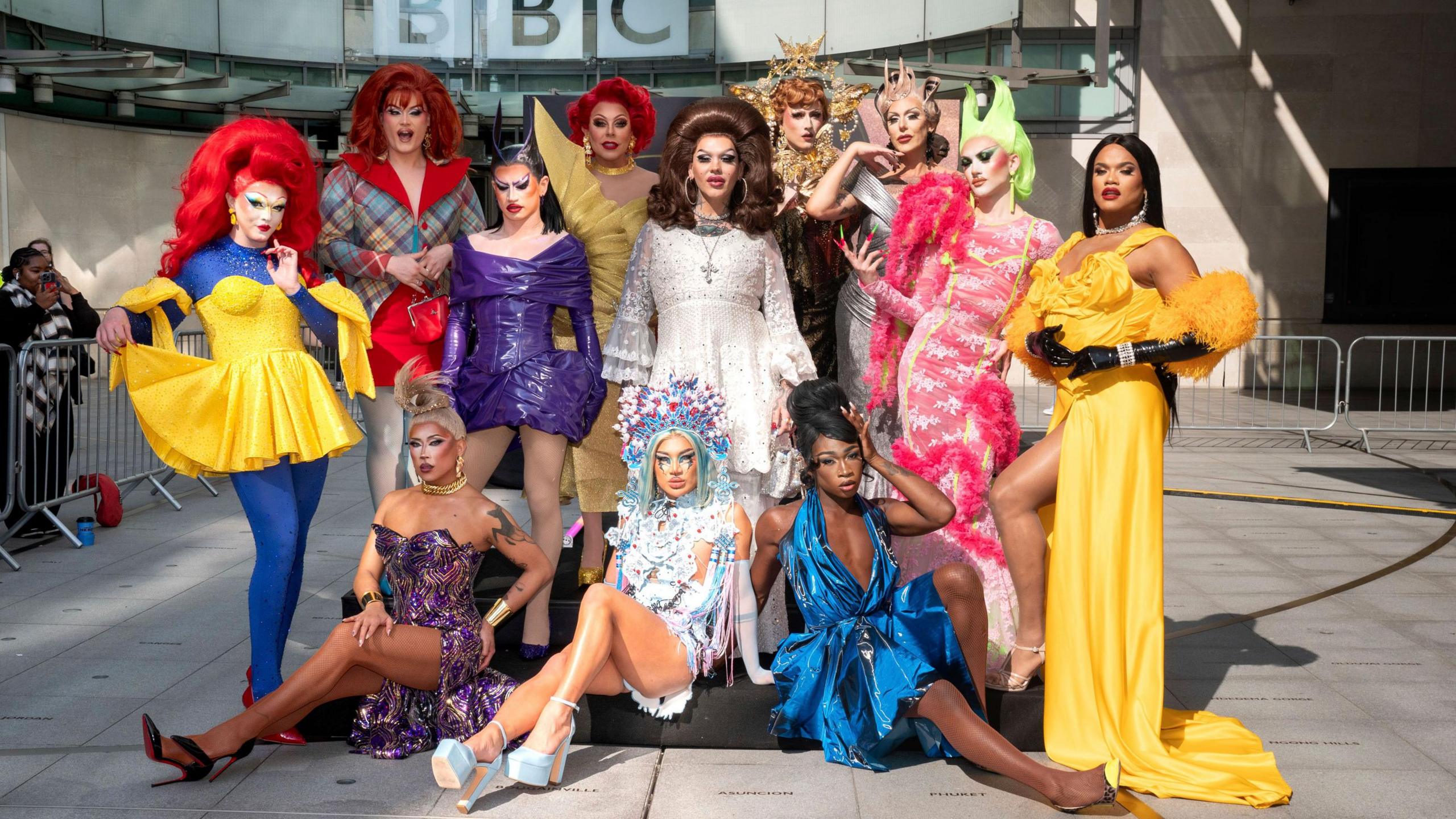 The 12 series six queens from Ru Paul's Drag Race UK pictured together outside the BBC's New Broadcasting House on a sunny day. 