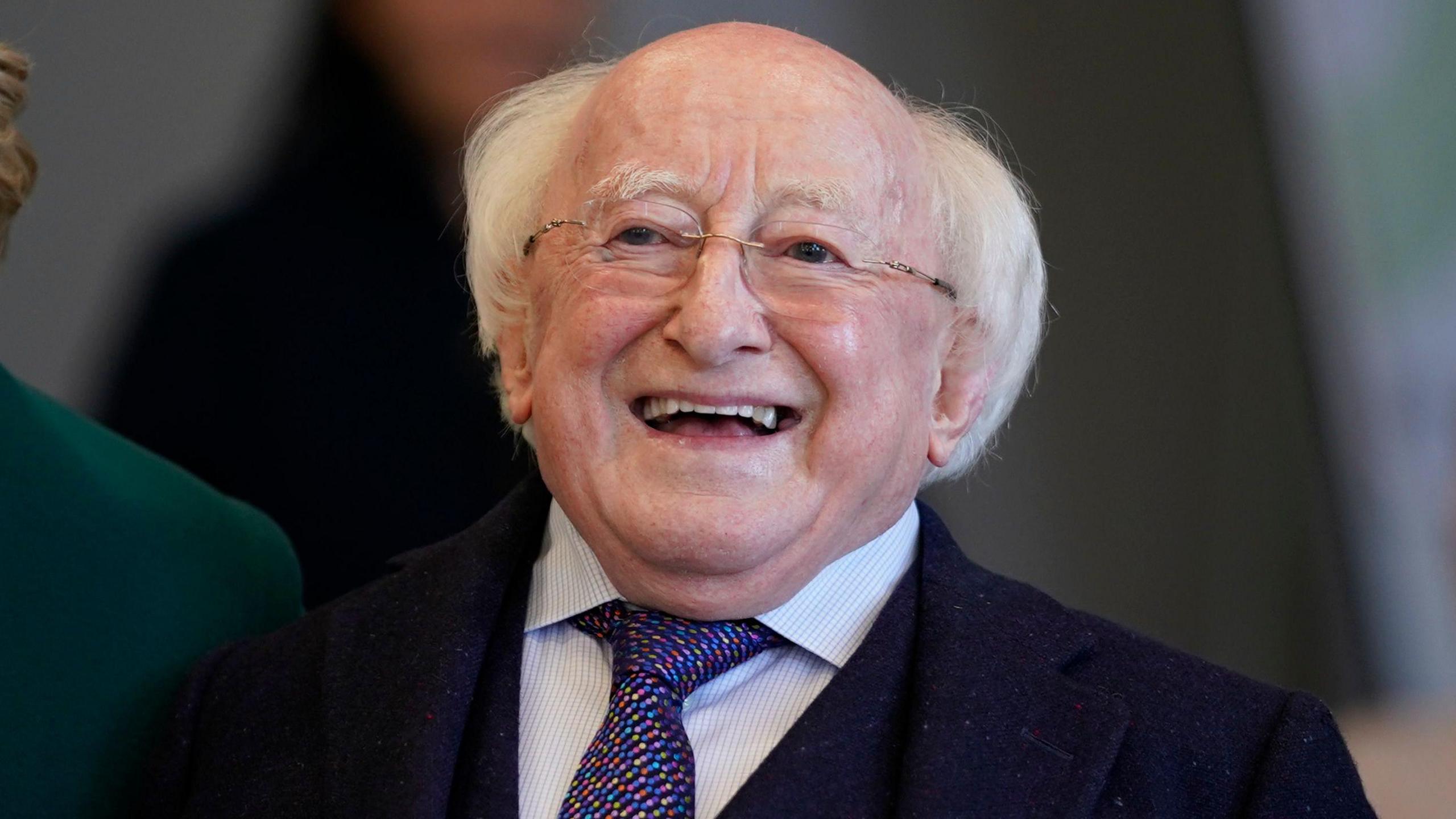 Ireland's President Michael D Higgins, pictured from the chest up. He has white hair. He's wearing a light blue top, tie and navy jacket. 