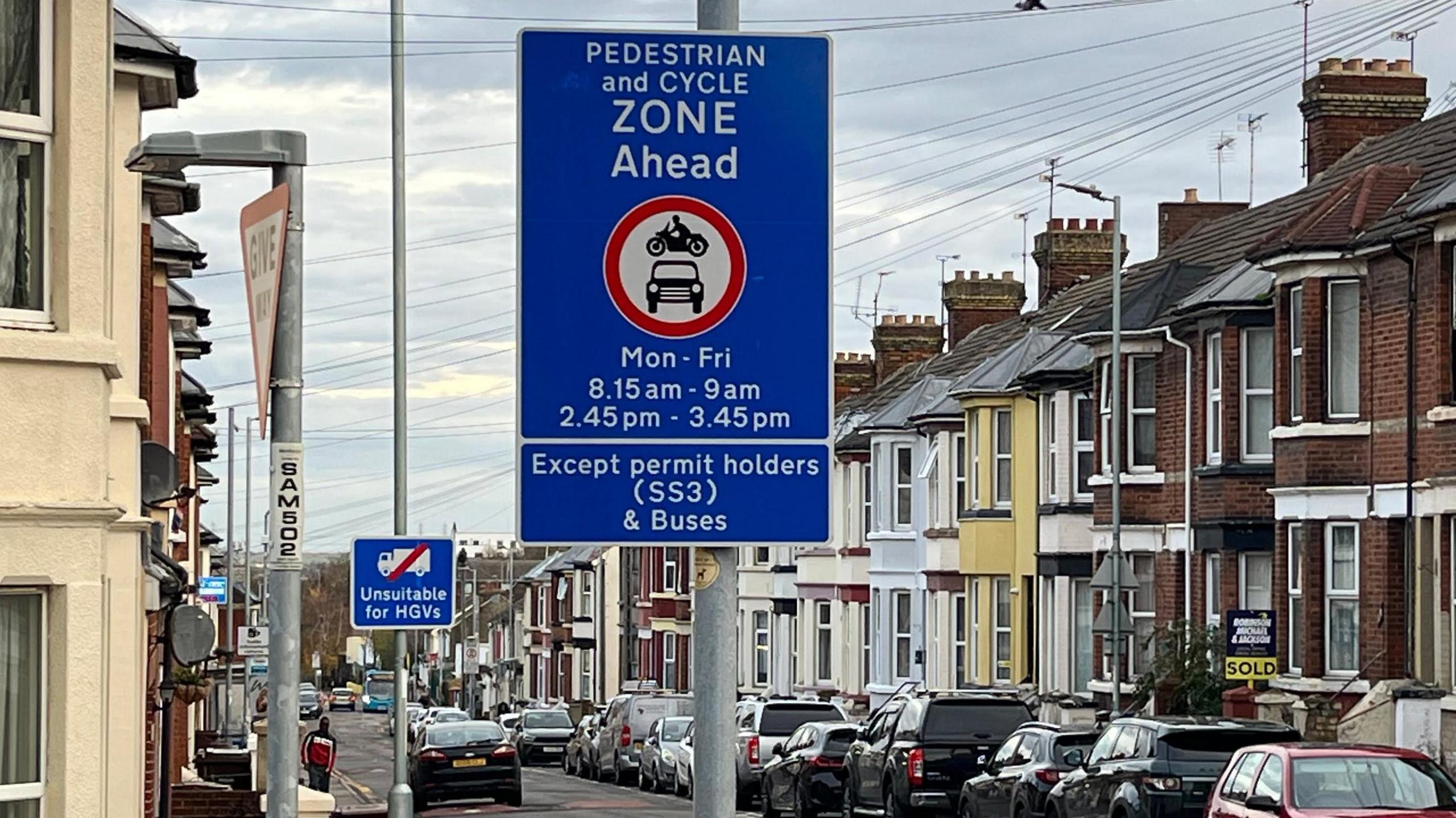 Blue sign on Richmond Road, Gillingham, which states a pedestrian and cycle zone is ahead with operating times running Monday to Friday between 8.15-9am and 2.45-3.45pm