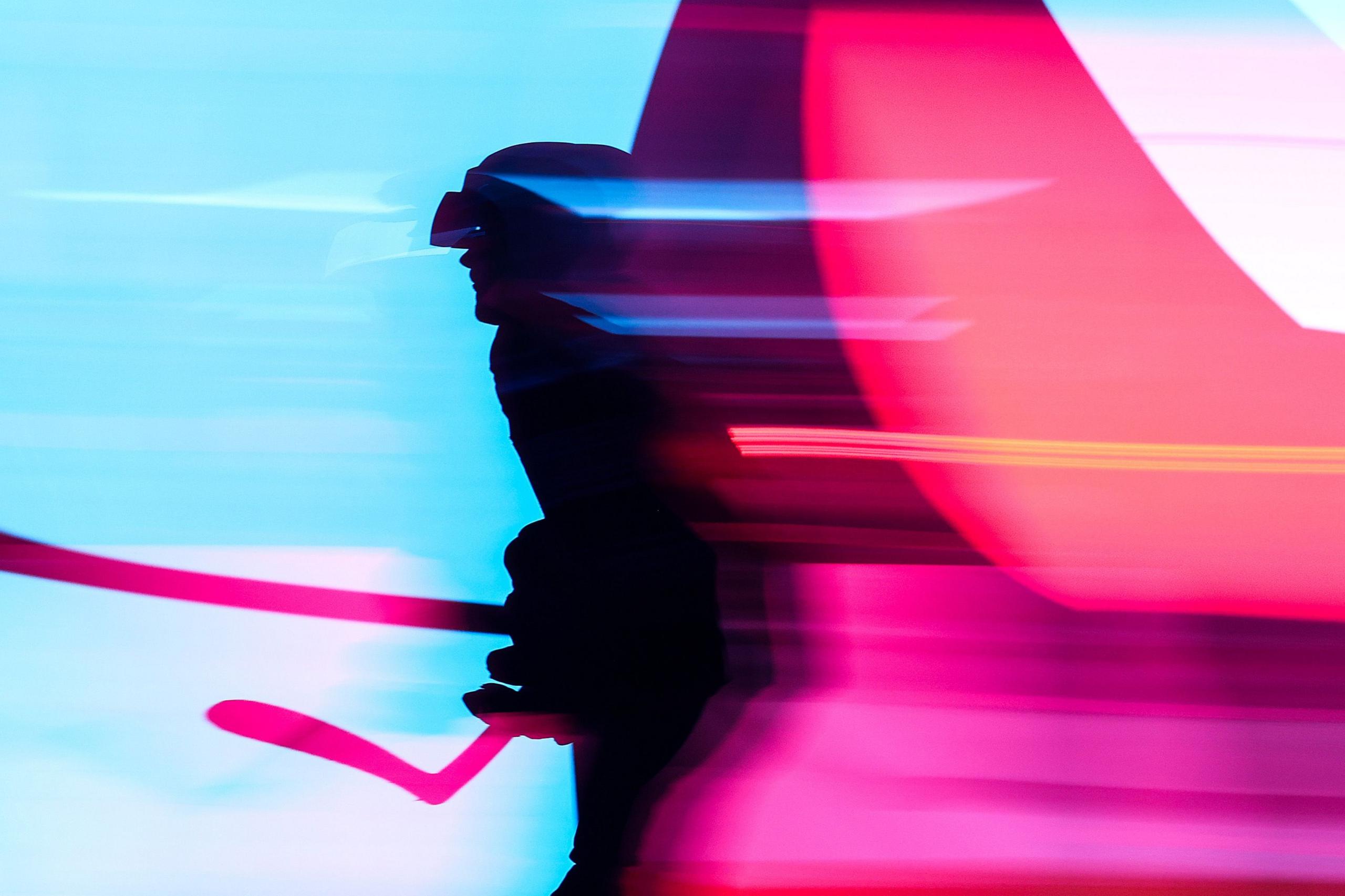 Silhouette of an ice hockey athlete, shown in motion blur against a vivid background of blue and pink light streaks, creating a dynamic, futuristic atmosphere with strong contrast and abstract shapes.