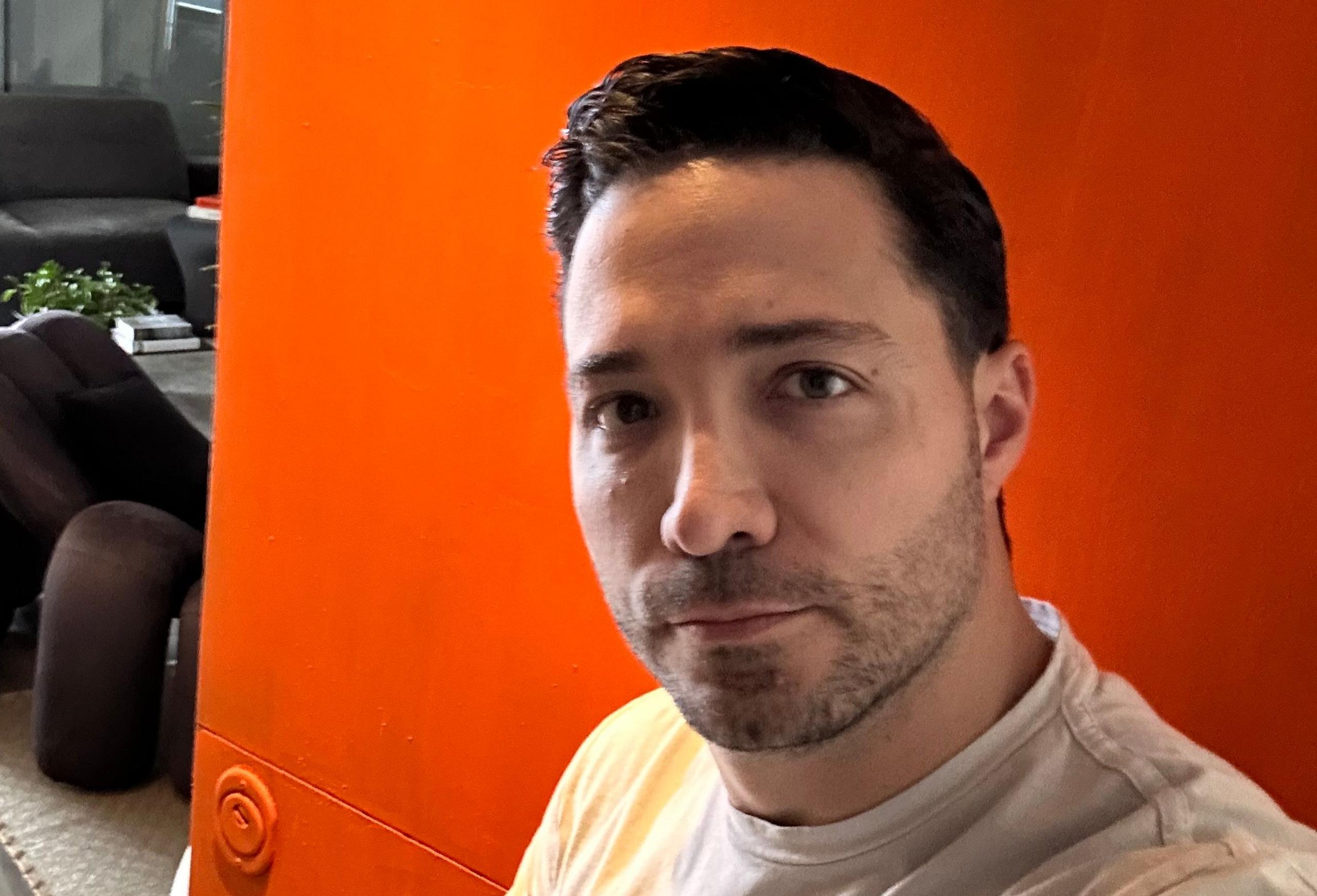 Juan Botero standing in front of his pumpkin-orange front door 