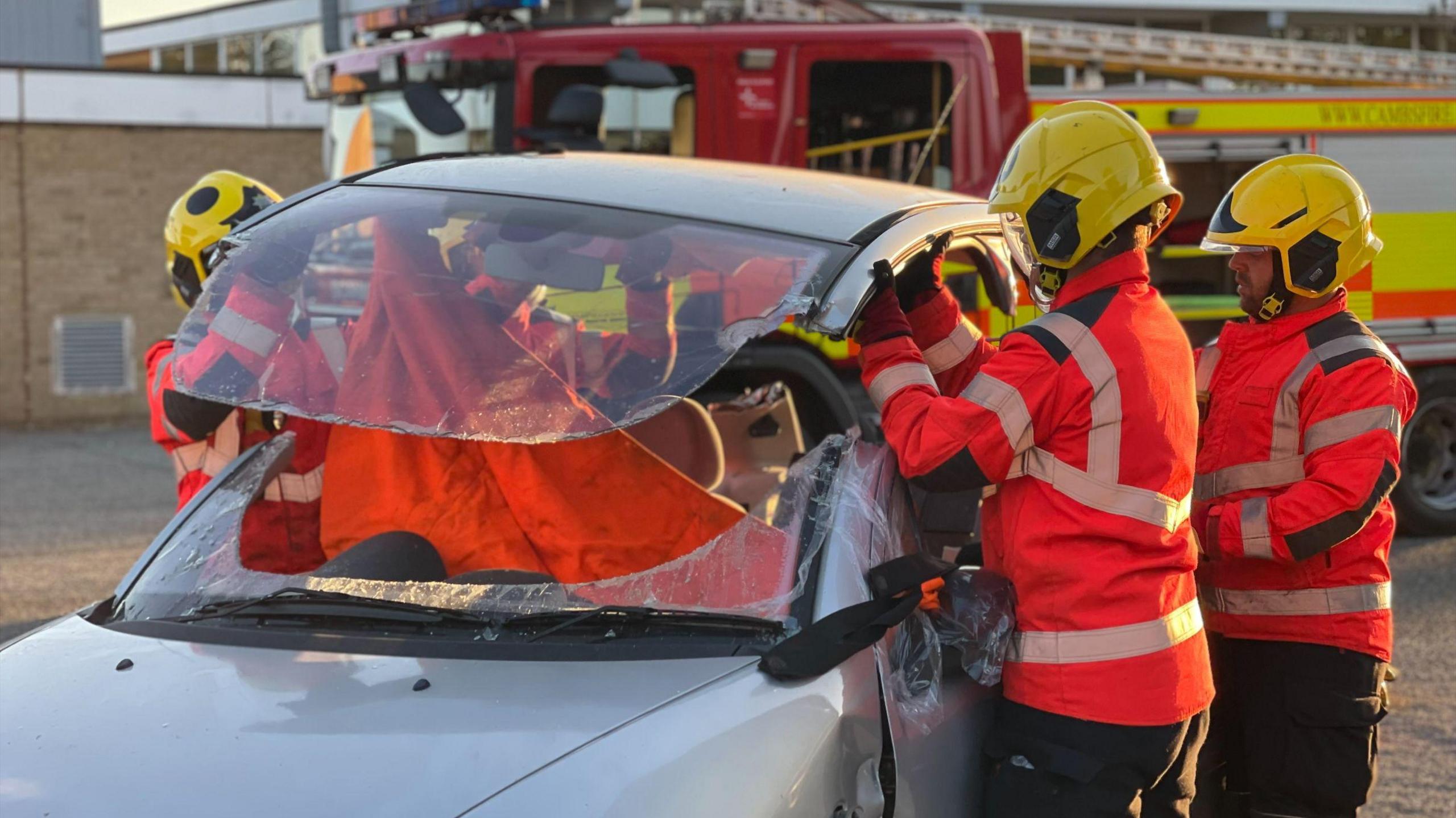 Firefighters have cut the roof of a car and are lifting it up during a training exercise.