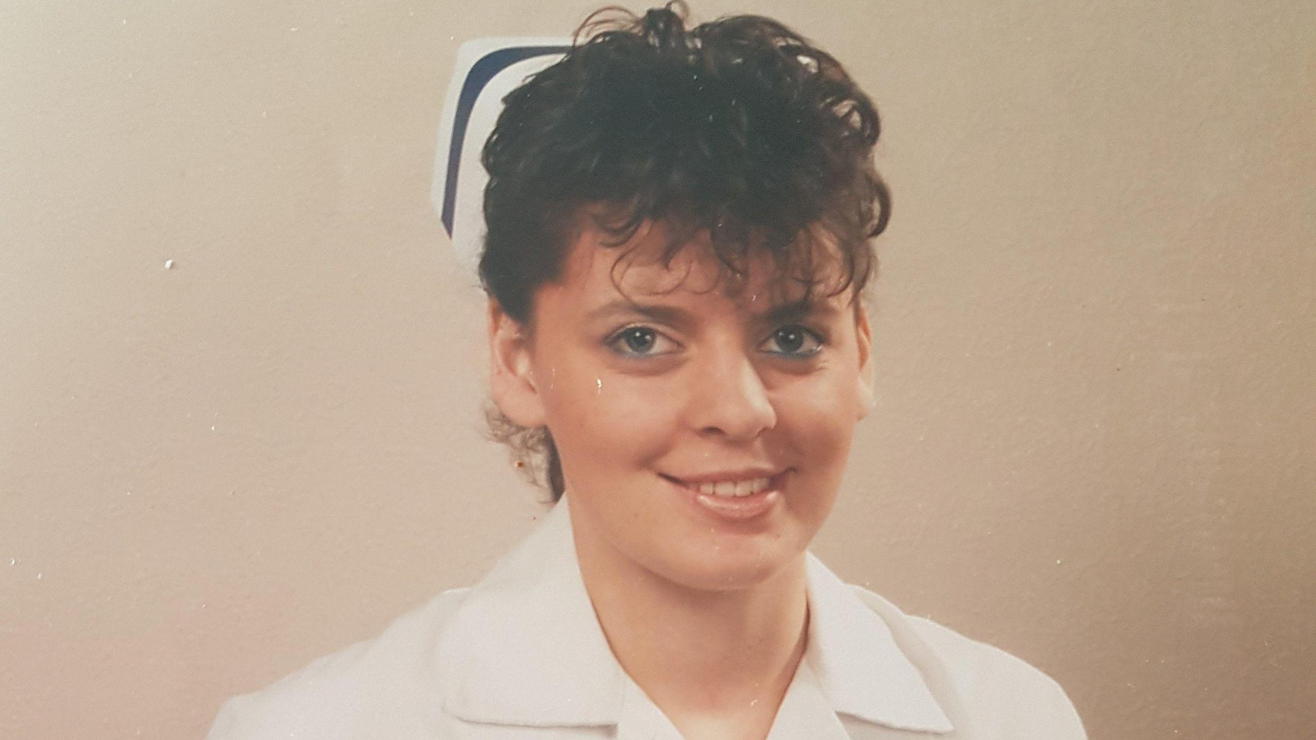 A soft focus posed pic of a nurse with a very eighties permed fringe and frosted lipstick. 