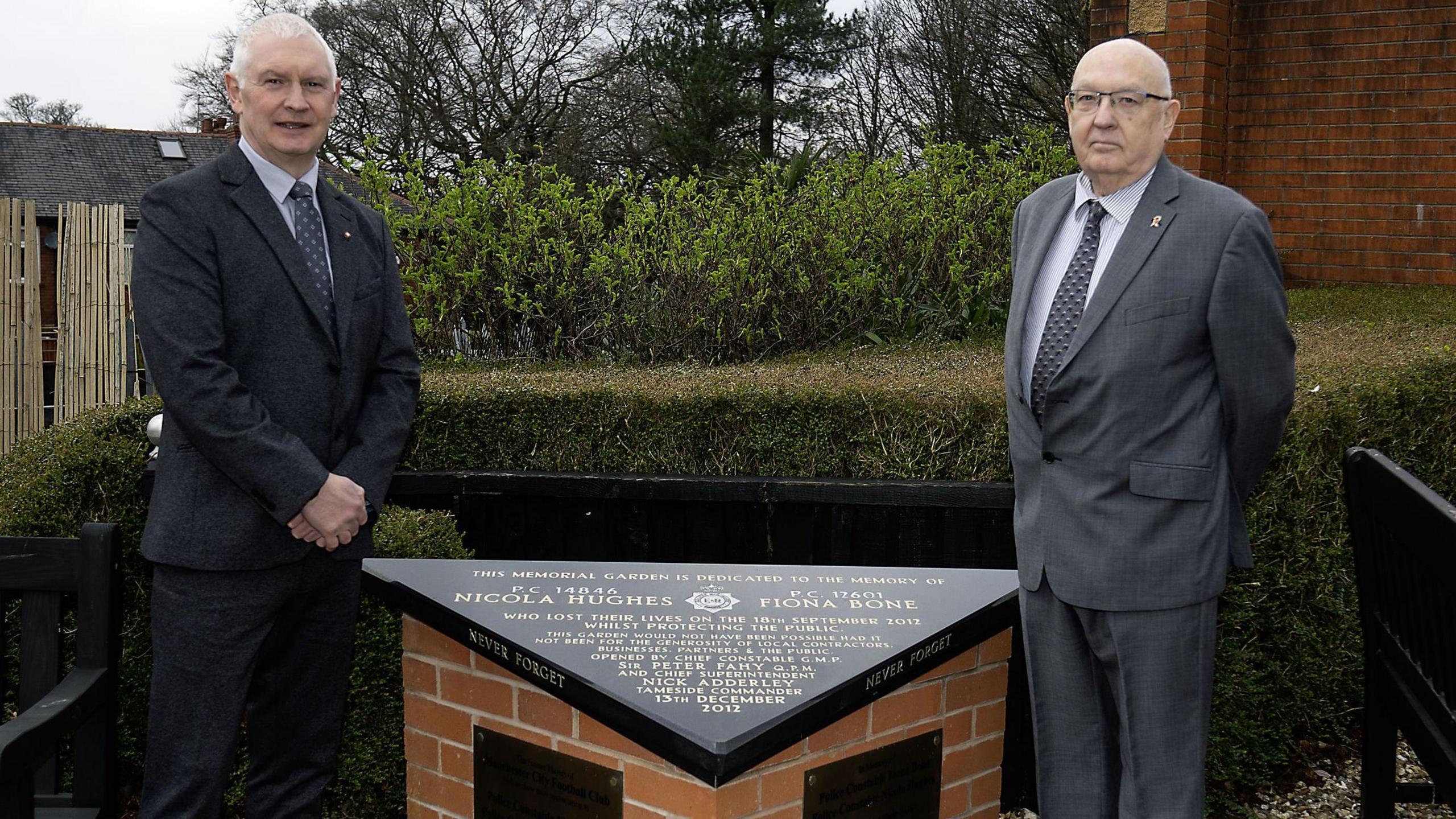 Bryn Hughes and Paul Bone (right) stood at the Hyde police station memorial garden in Manchester. They are beside a triangular memorial to killed police officers Nicola Hughes and Fiona Bone.