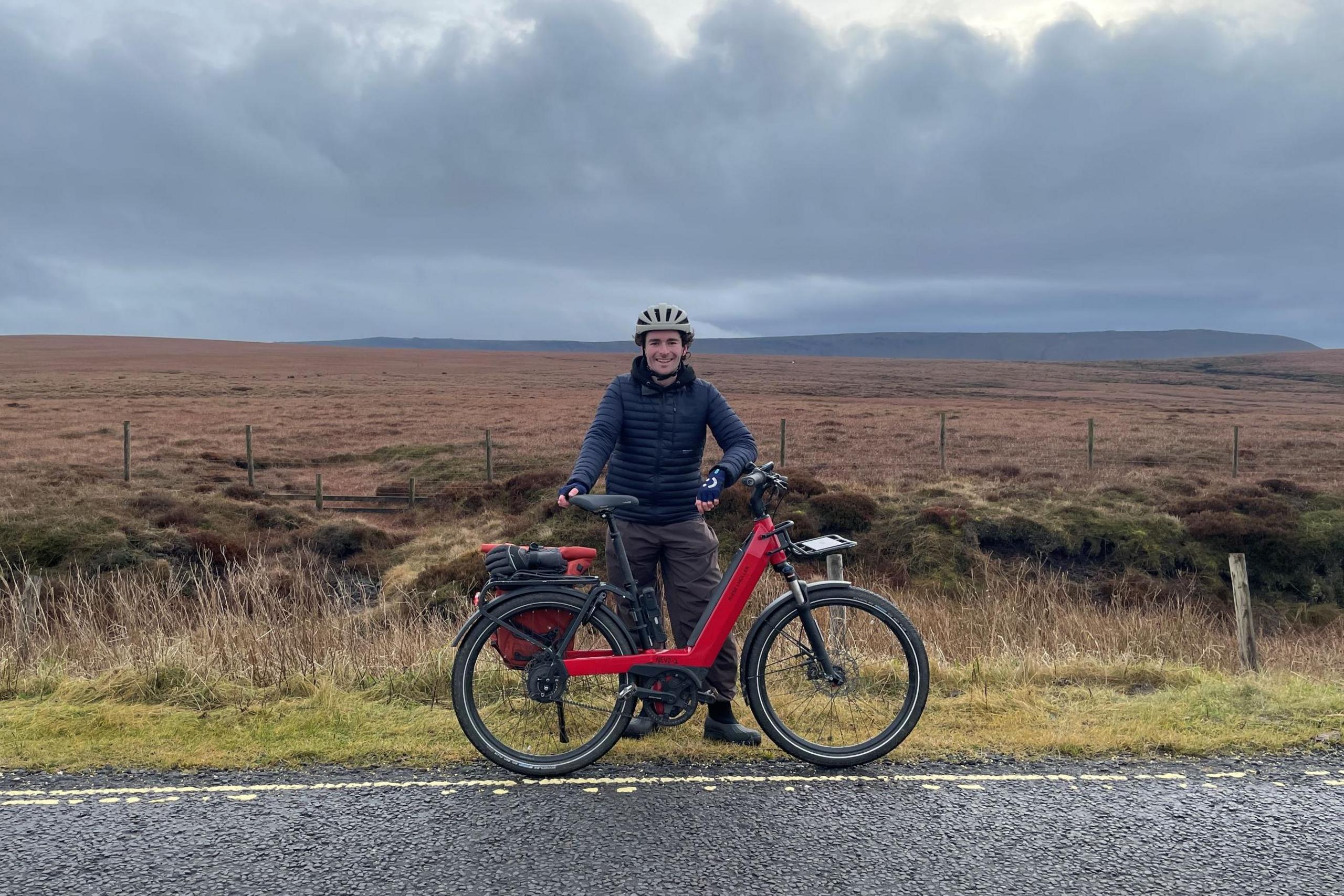 Harry Gray stands next to his bike at the side of the A57 Snake Pass