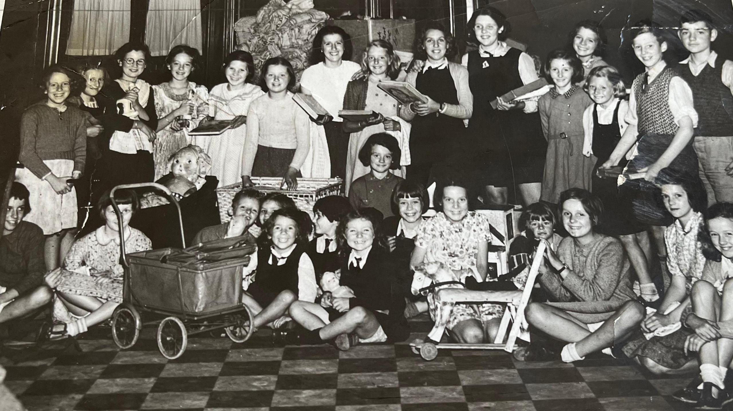 A group of children gathered in the town hall with various toys.