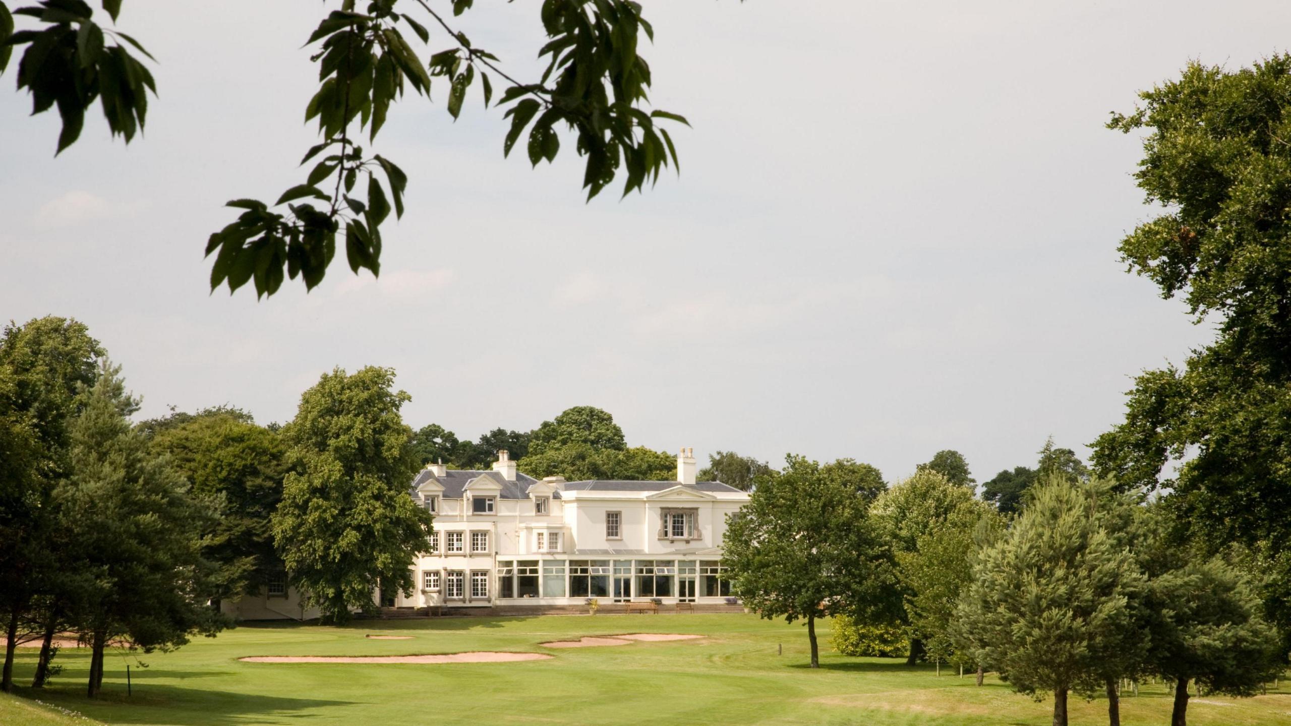 Beeston Fields Golf Club  - it is a white building with grass in front of it surrounded by green trees