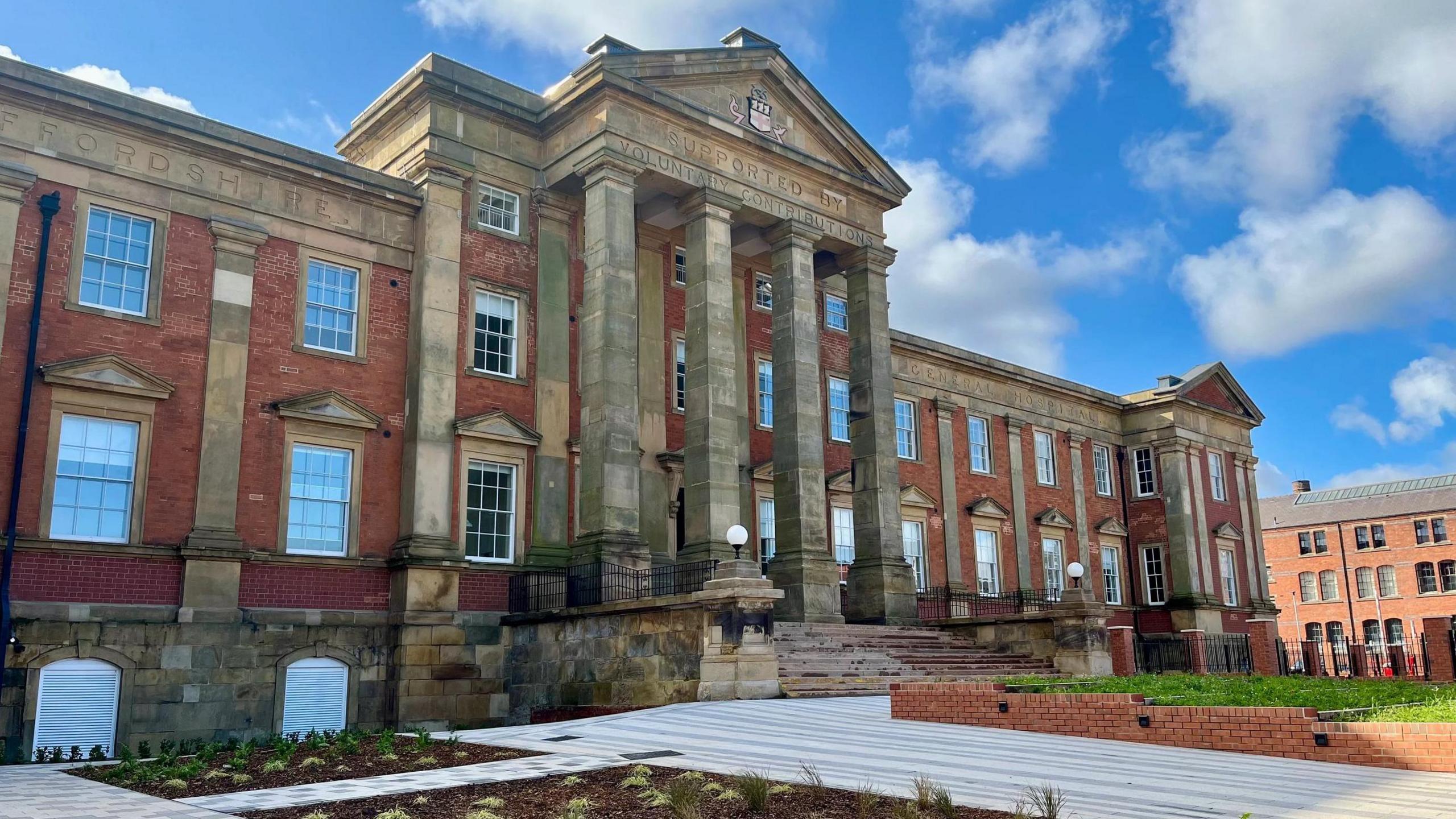 The development building still has the old hospital exterior with columns at the entrance and steps leading up to the front door.