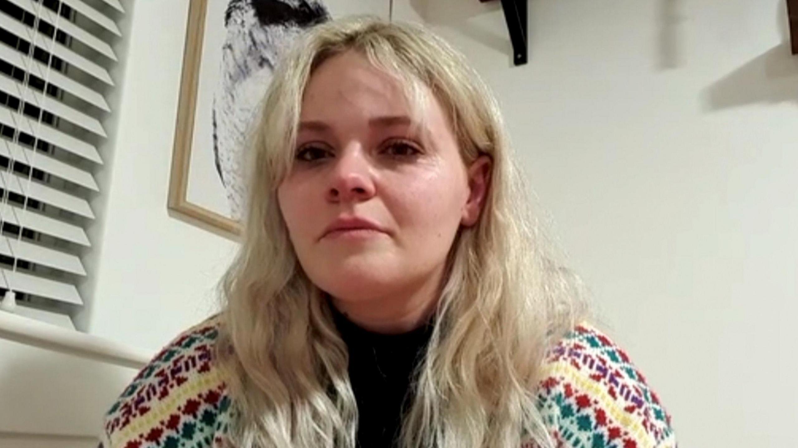 Hannah Gidman, who has long blonde hair and is wearing a multi-coloured cardigan, is photographed looking at the camera