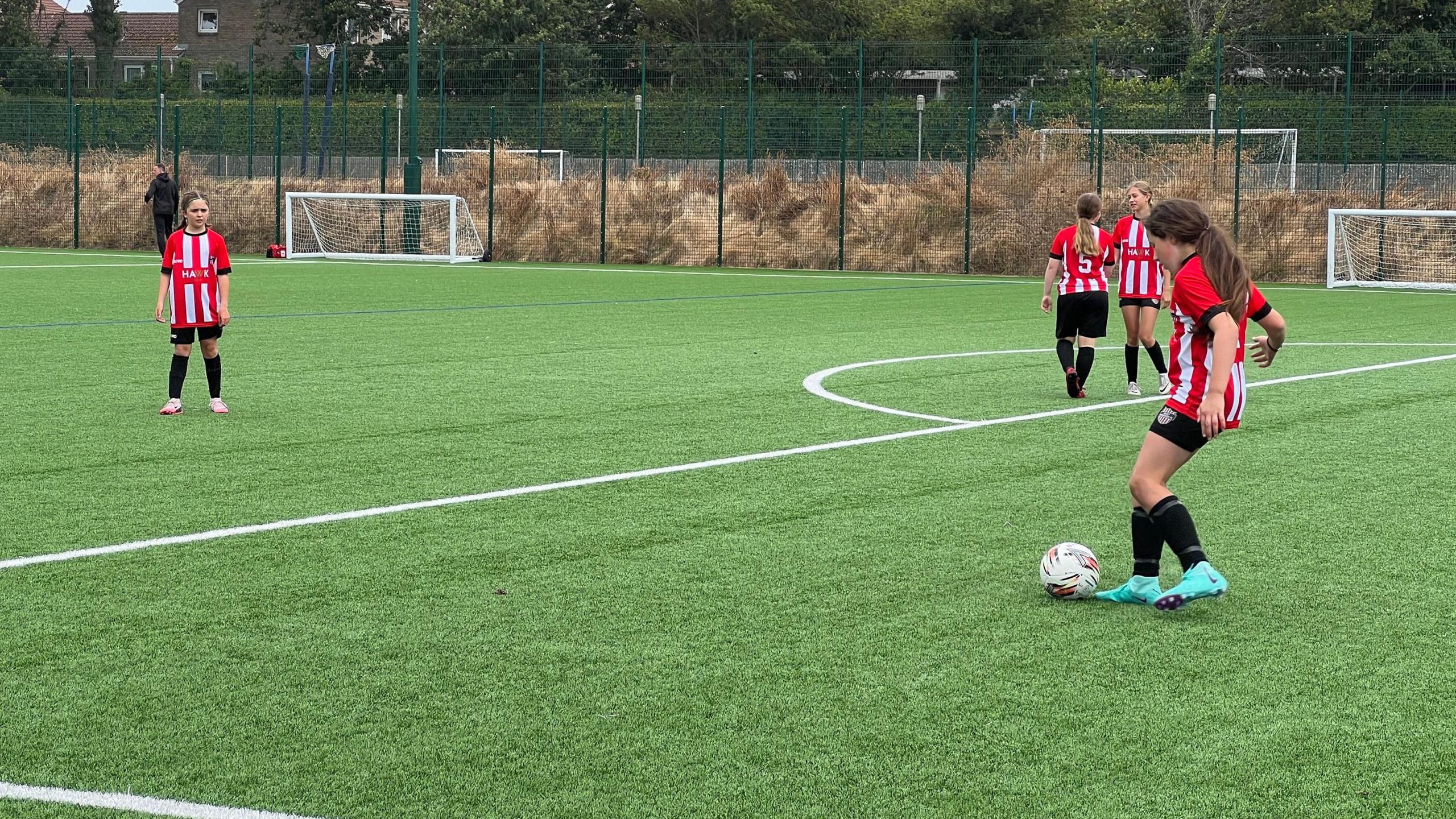 A girl gets ready to pass to another girl on a pitch