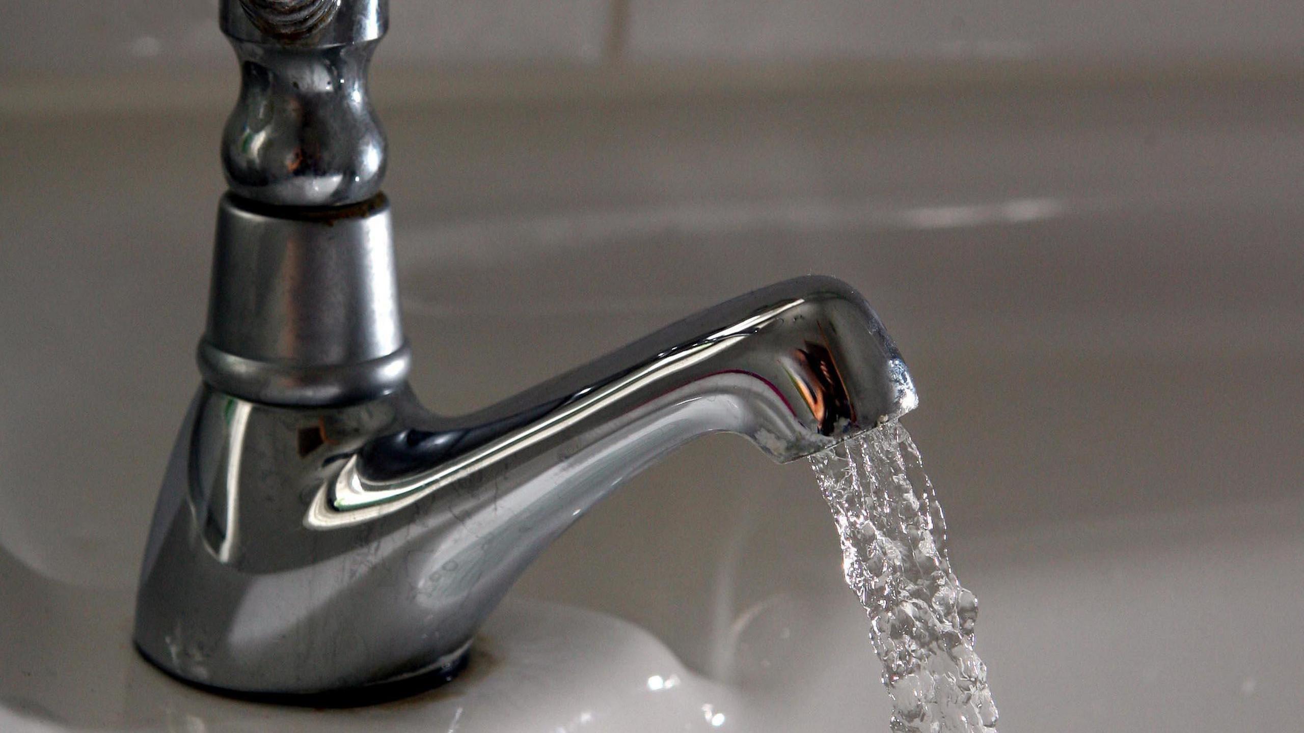 A tap with water running out of it into a sink. 