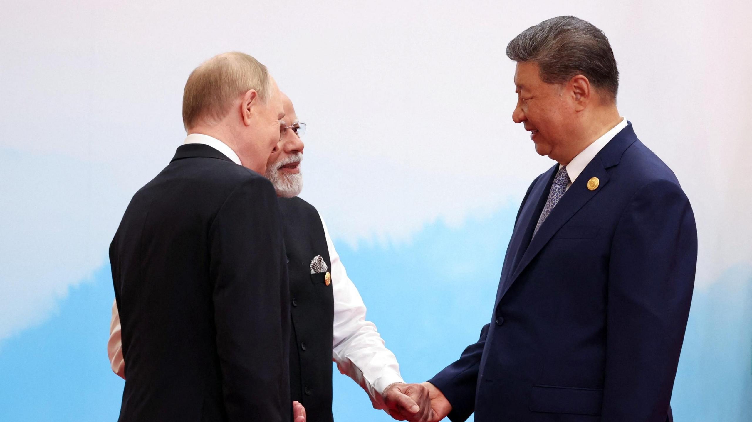Chinese President Xi Jinping, Indian Prime Minister Narendra Modi and Russian President Vladimir Putin speak with Xi holding Modi's hand