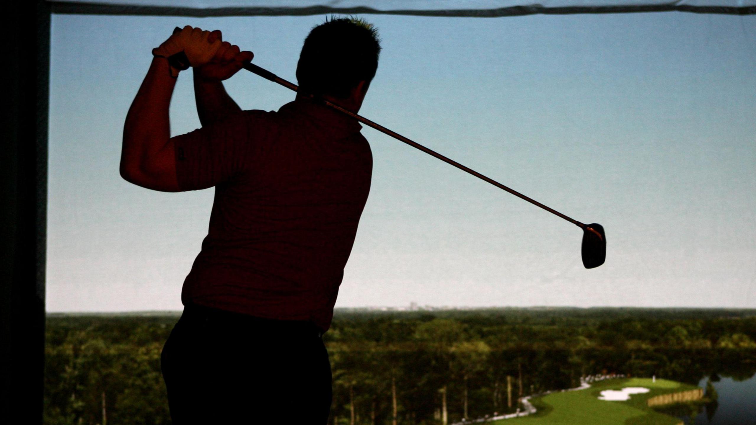 A man hitting a shot on an indoor golf simulator