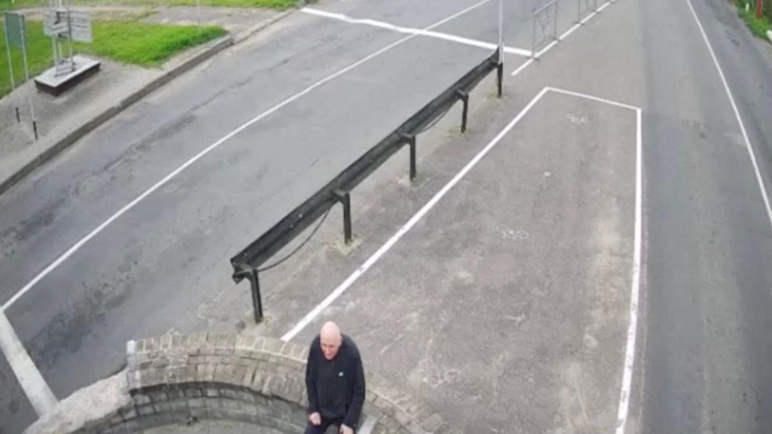 A man sits on a wall at the border