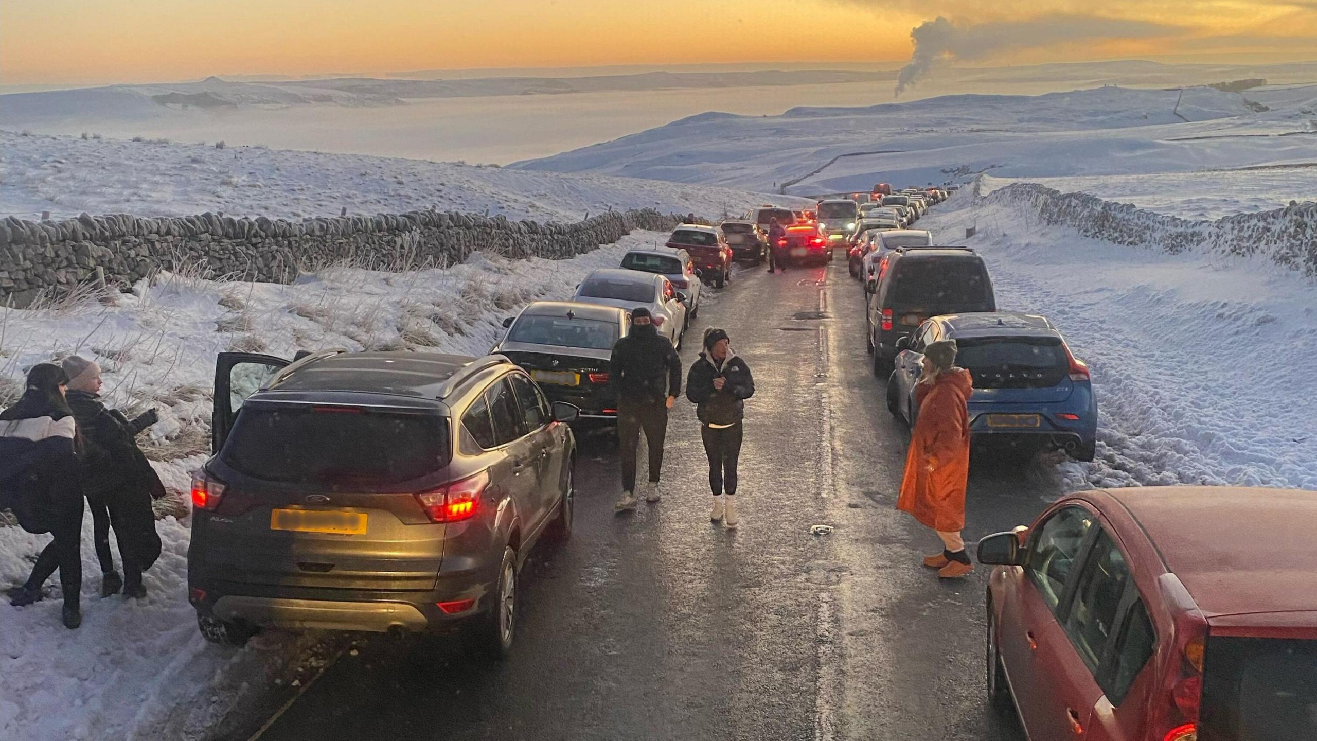 Cars along both sides of a snowy road high up in the Peaks