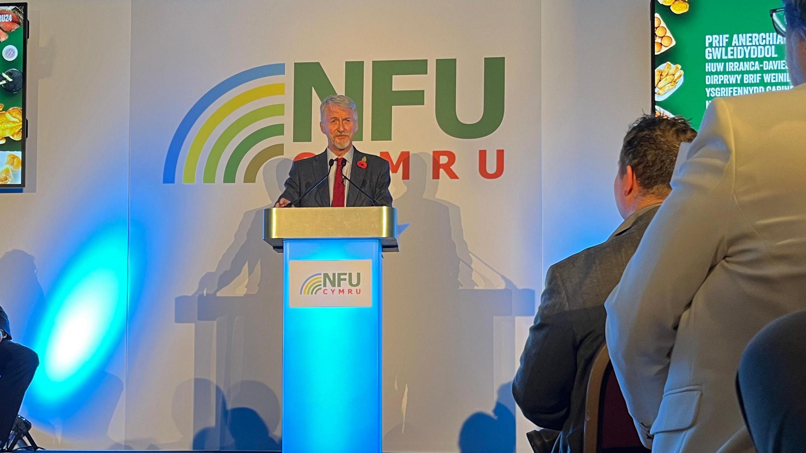 Huw Irranca-Davies stood at a podium with NFU Cymru logo behind him