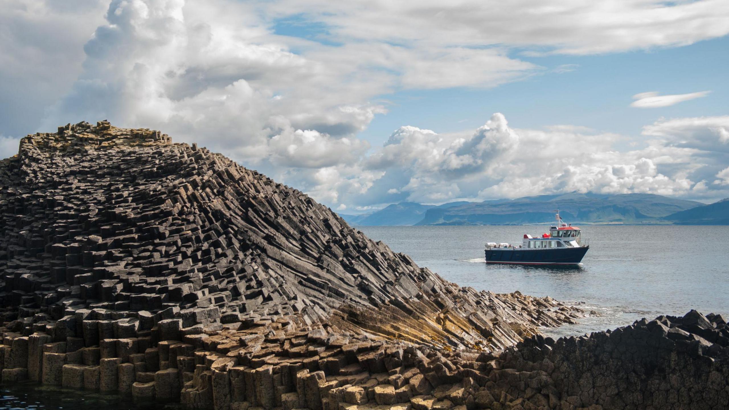 A tour boat passes Staffa and one of its basalt rock formations.