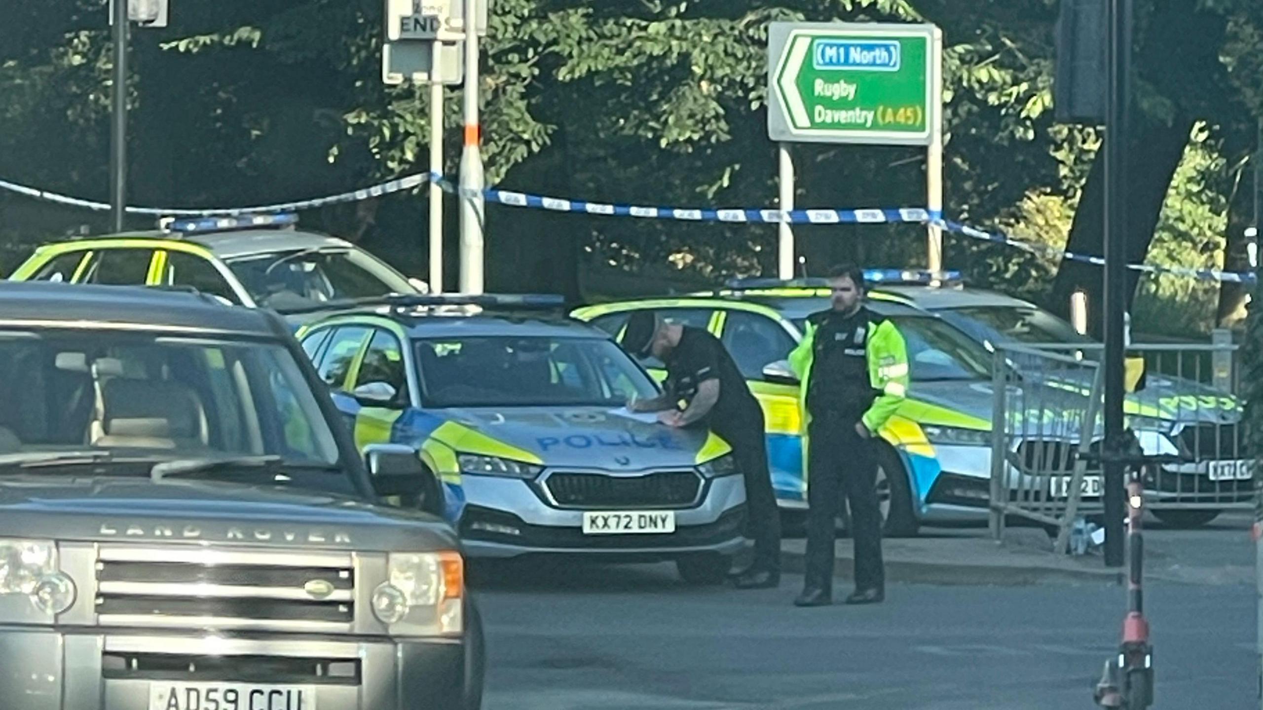 Police tape sealing off St Andrew's Road with five police cars visible