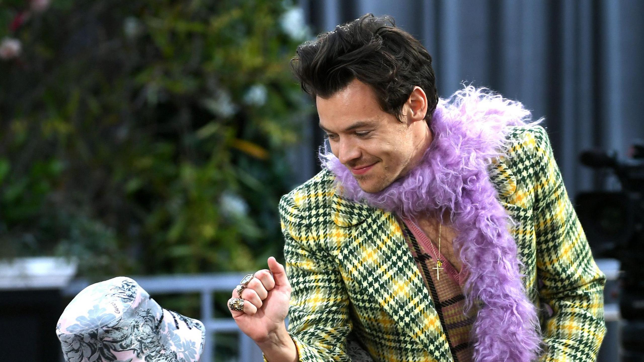 Harry Styles bows and interacts with a fan at the 2021 Grammys, where he wore the yellow, purple and pink outfit depicted in the mural