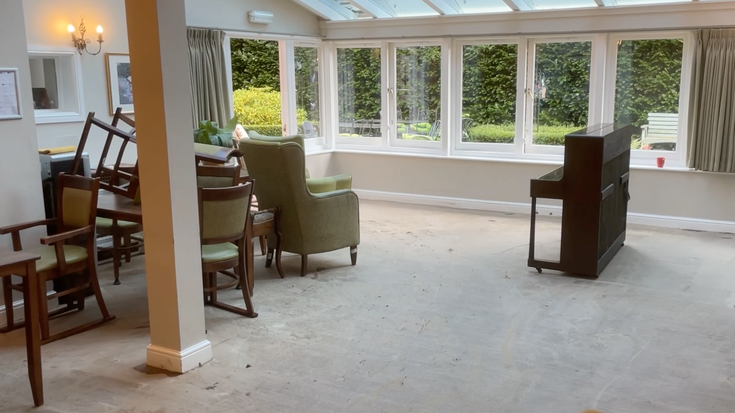 The ground floor of the care home with a piano, chairs and windows