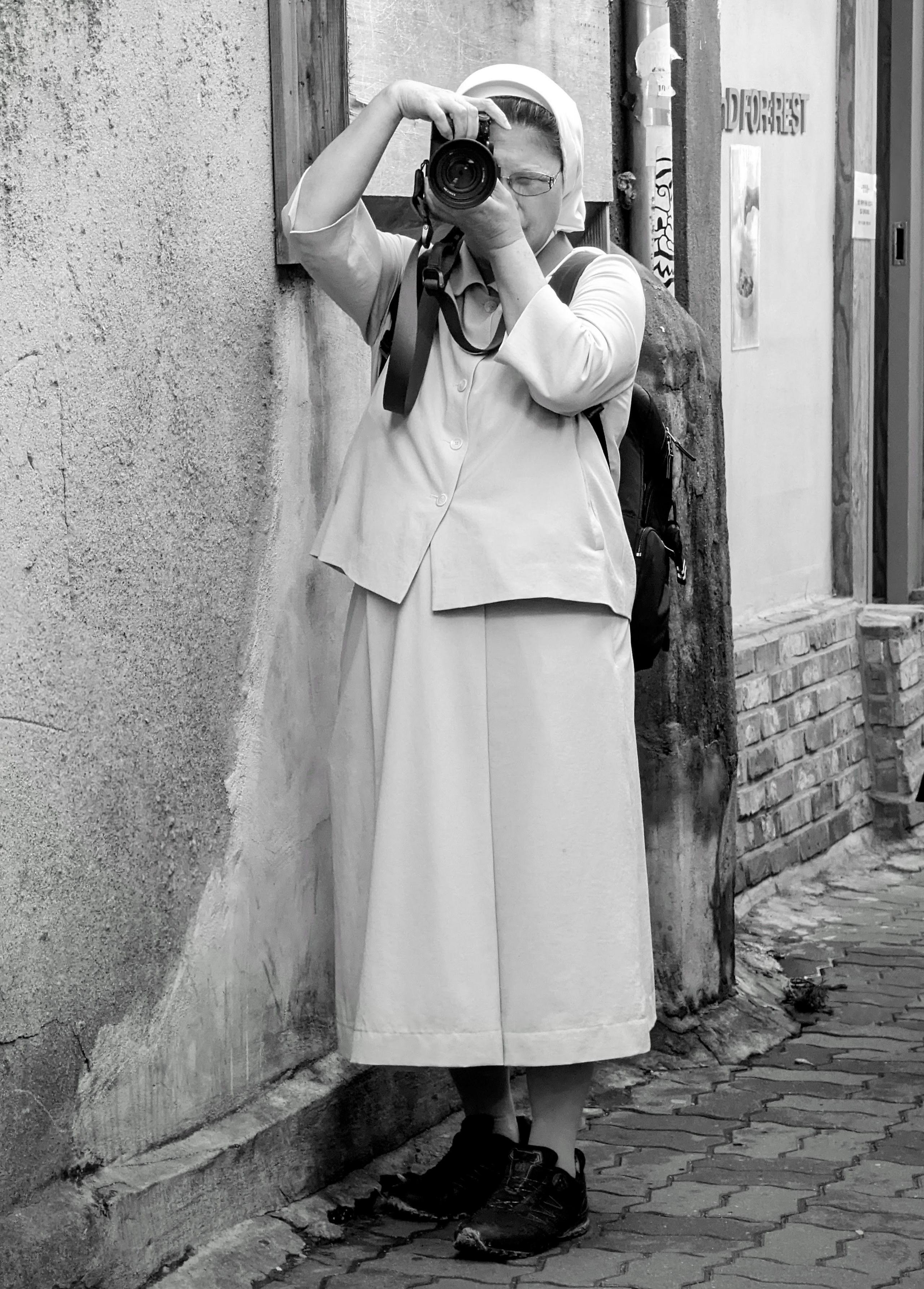 A nun takes a picture with a camera