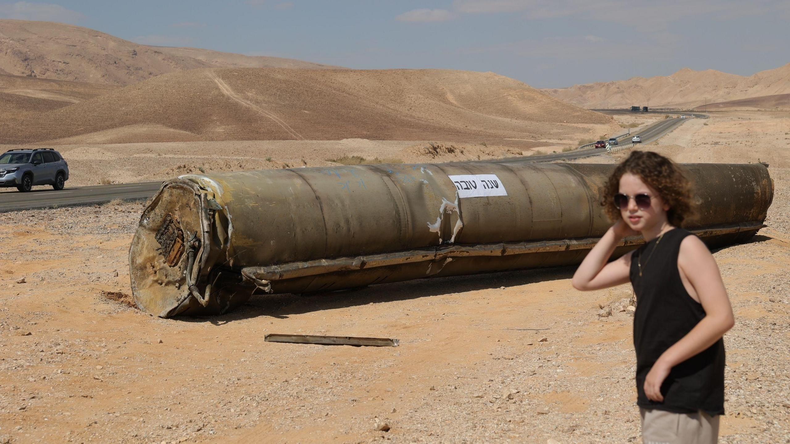 Woman walks past wreckage of Iranian missile with the words "Happy New Year" written on it, near the southern Israeli city of Arad