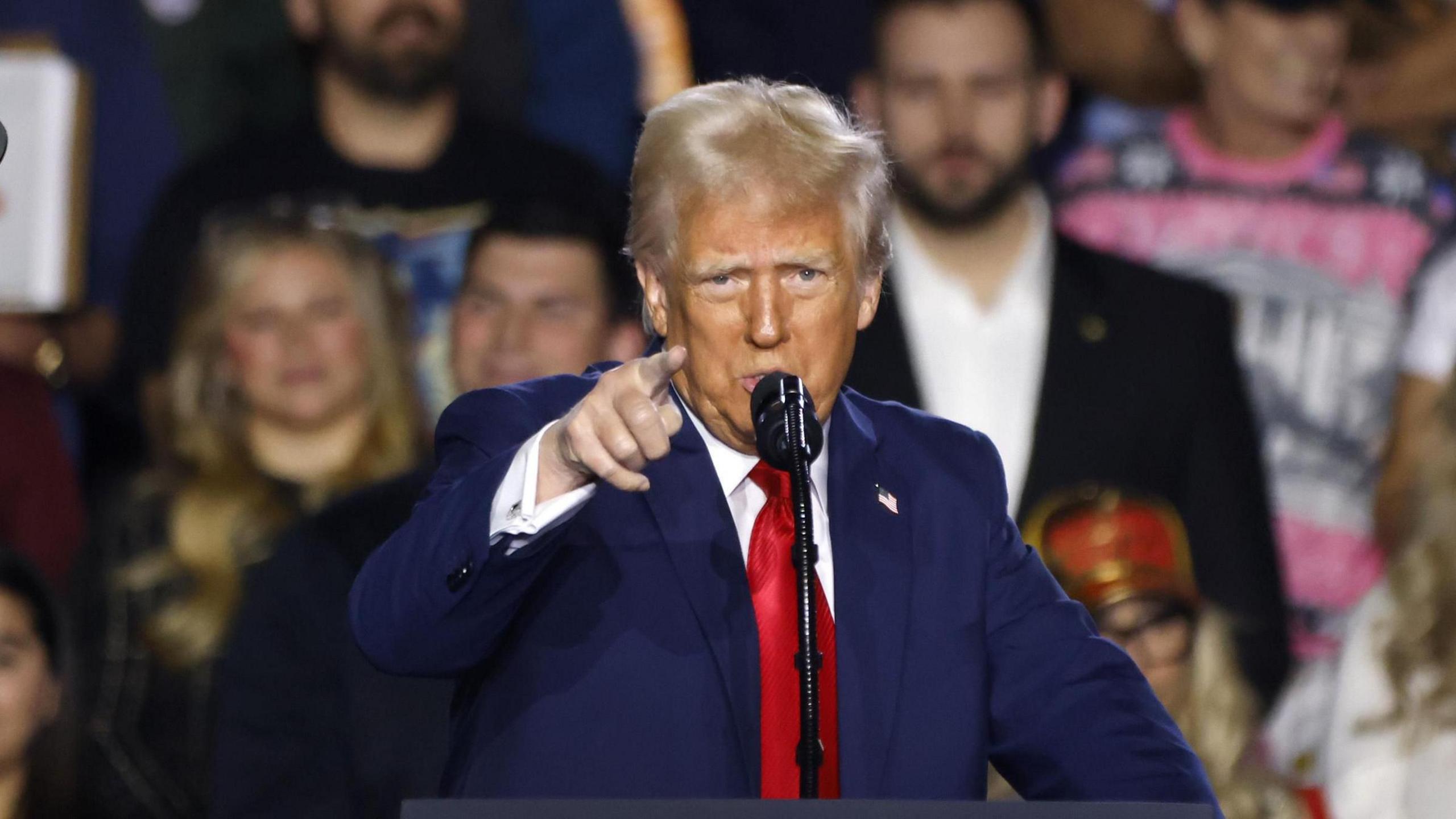 Donald Trump, wearing a blue suit and red tie, gestures with his right hand as he speaks at an event in Las Vegas on 24 January