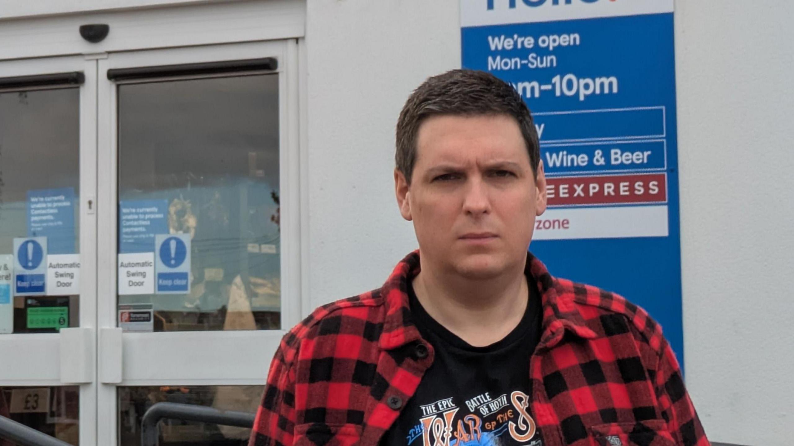 Man stands in front of shop.