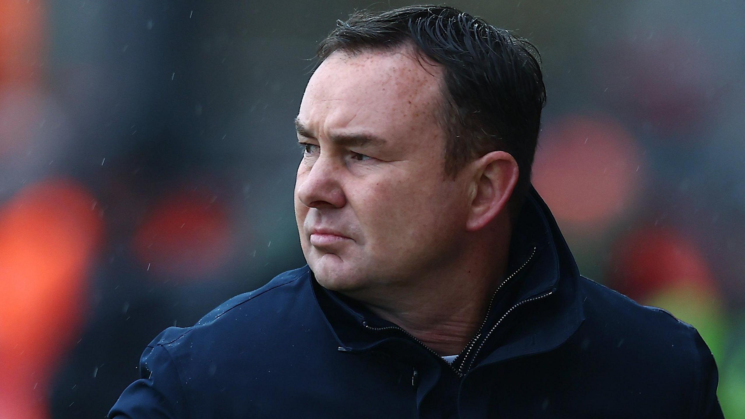 Morecambe boss Derek Adams watching his team play at the Mazuma Stadium 