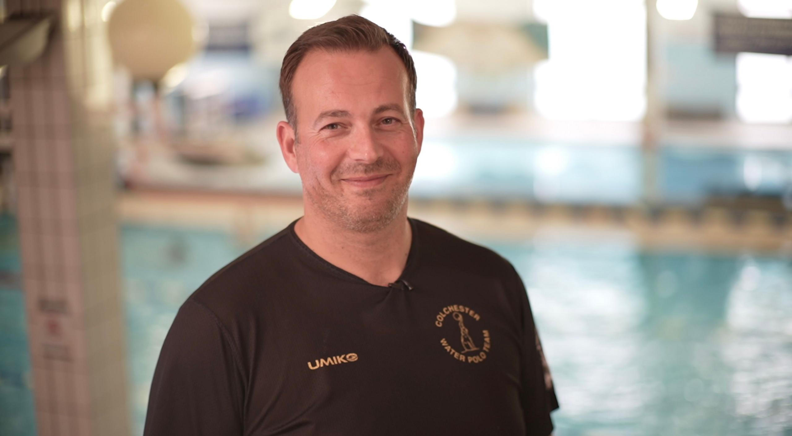 Martin Vinter smiles at the camera inside a leisure centre. He has short brown hair and wears a black T-shirt.