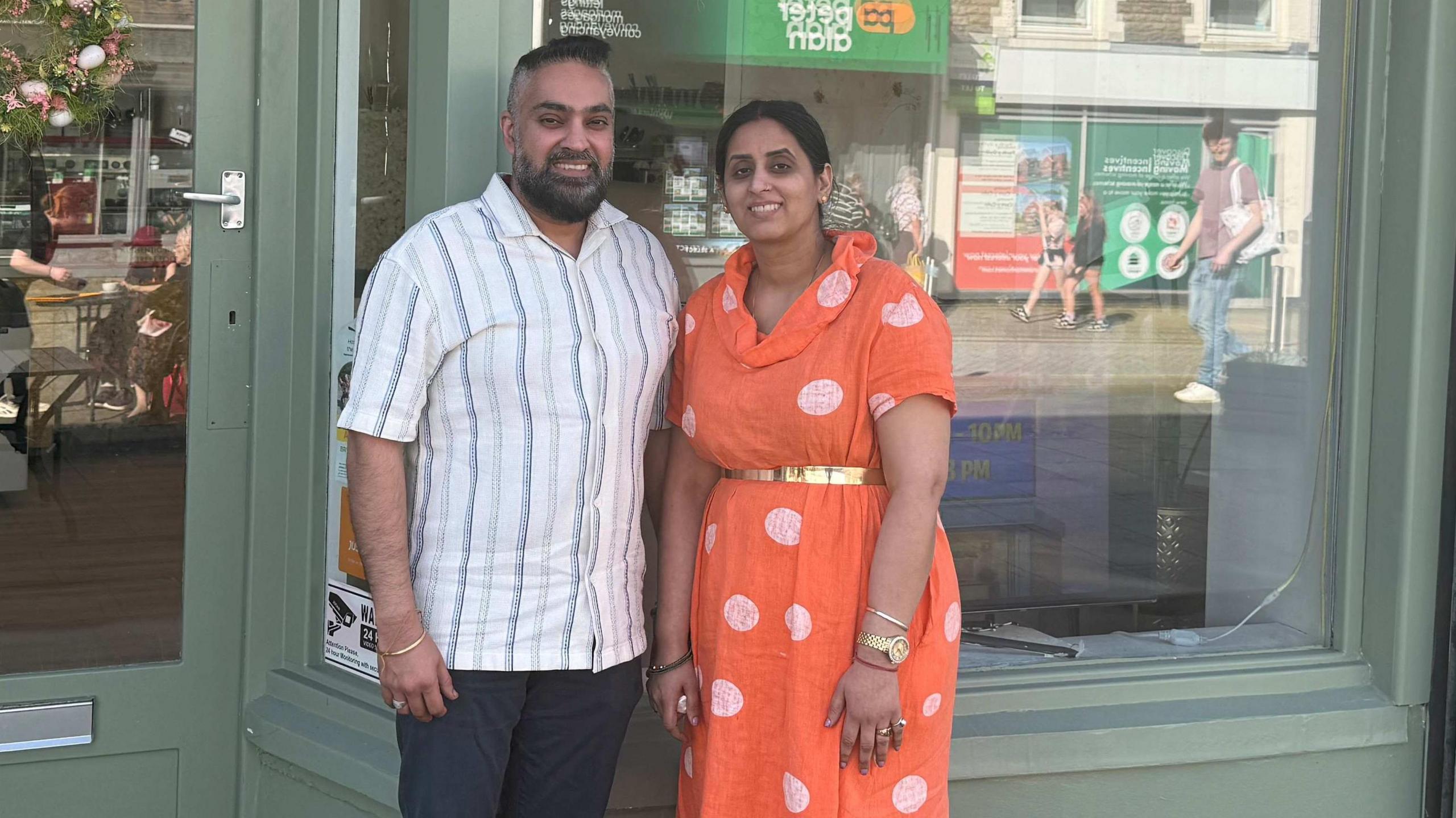 A couple stand outside a shop 