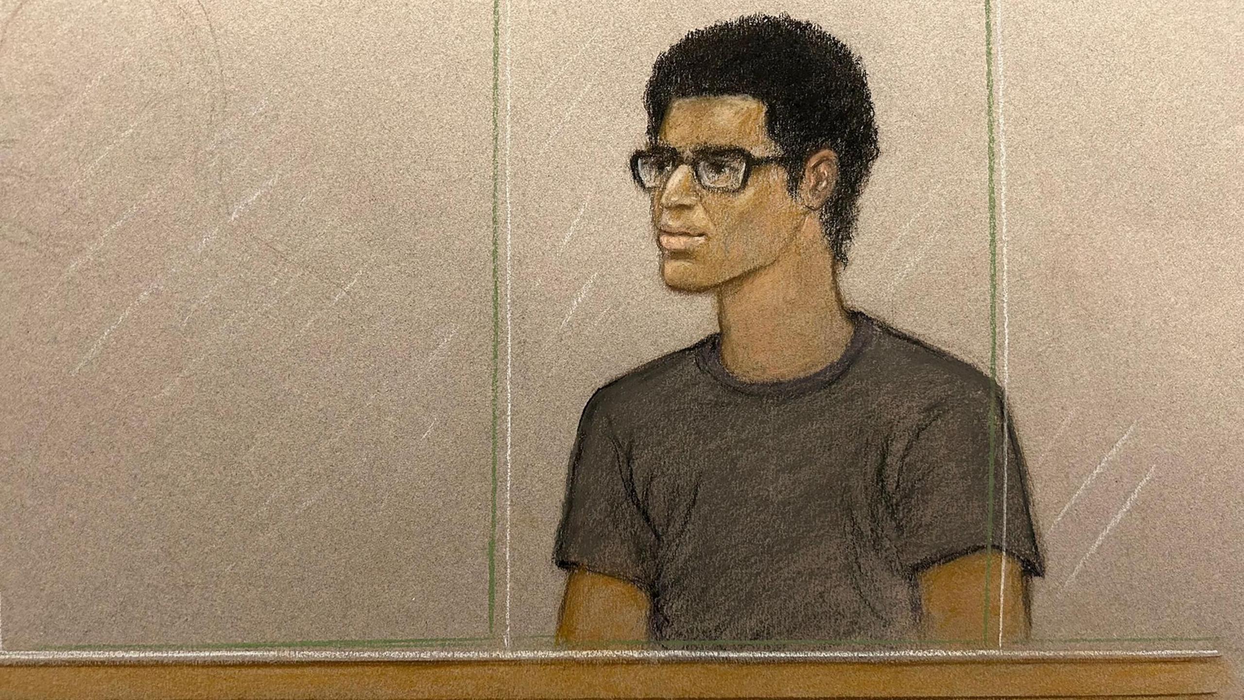 Court sketch of Nicholas Prosper appearing in the dock at Luton Crown Court, Bedfordshire. He has a dark top and black rimmed glasses.