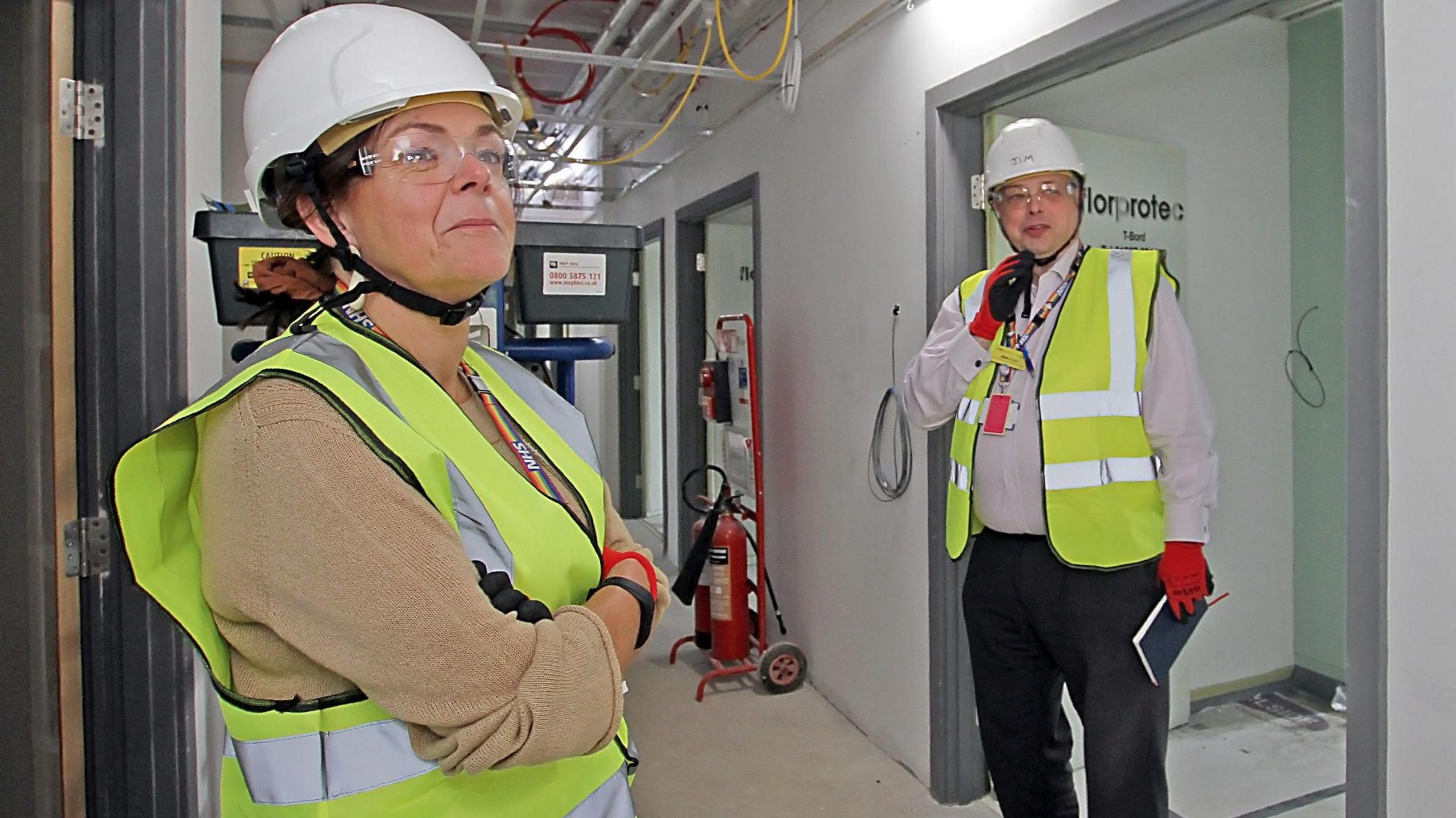 Tracy Allen and Jim Austin, from the health trust, wearing high vis jackets and hard hats in the new building while it was under construction