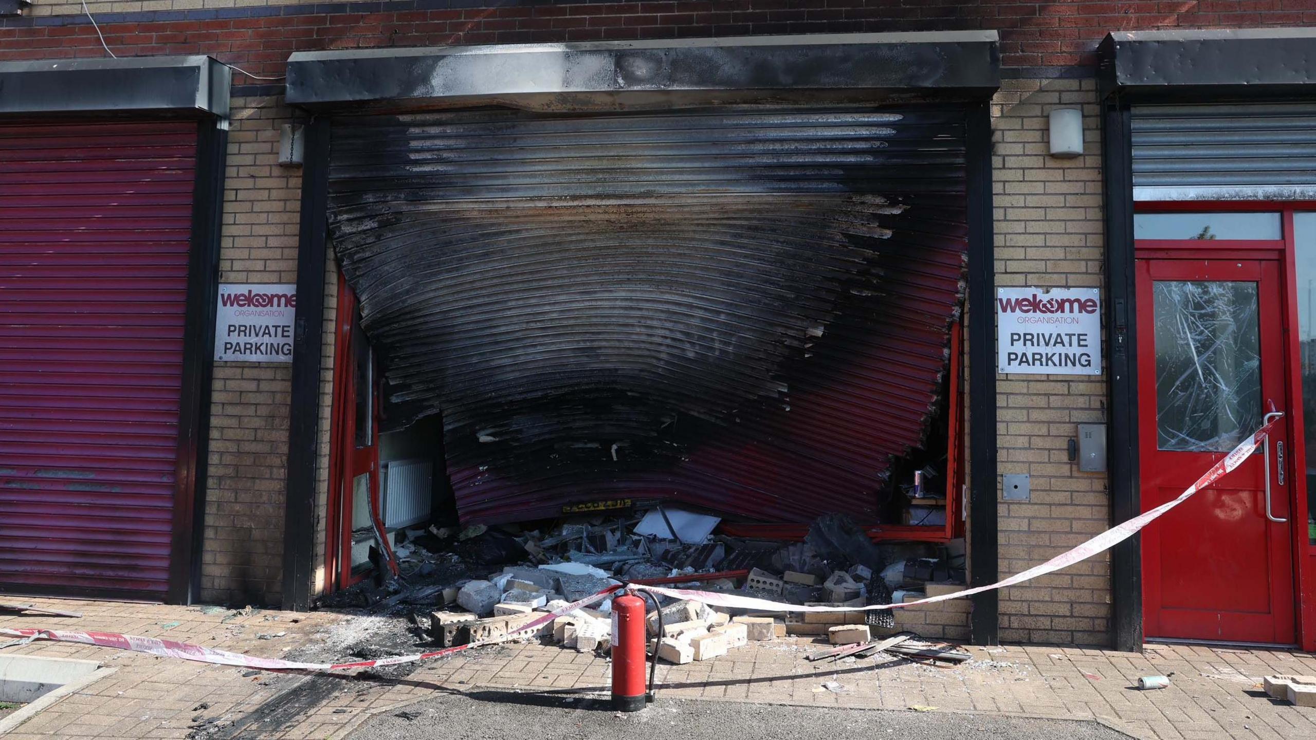 The exterior of the Welcome Organisation building with a burned garage door which is warped