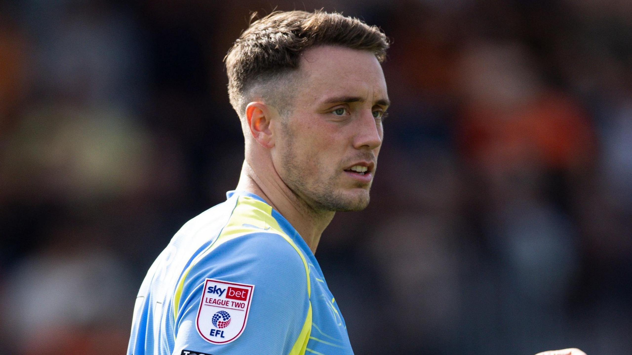 A side-on headshot of Toby Mullarkey wearing a sky blue away kit for Fleetwood