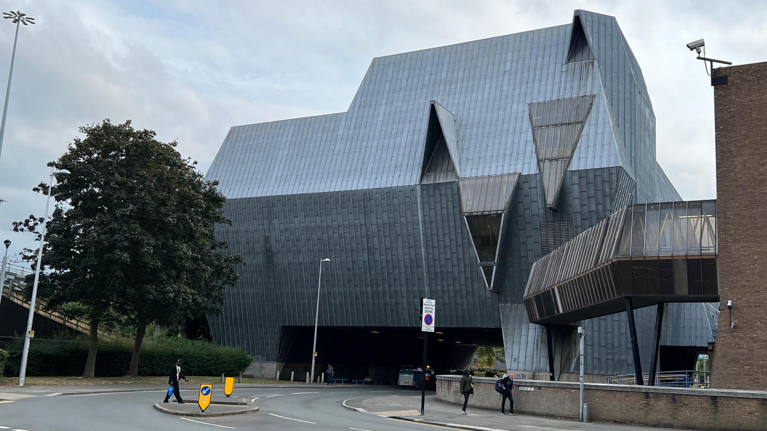A large grey building known locally as "The Elephant" straddles a road in Coventry city centre. It's a building of multiple angles and grey slates down the sides and on the roof of the building.