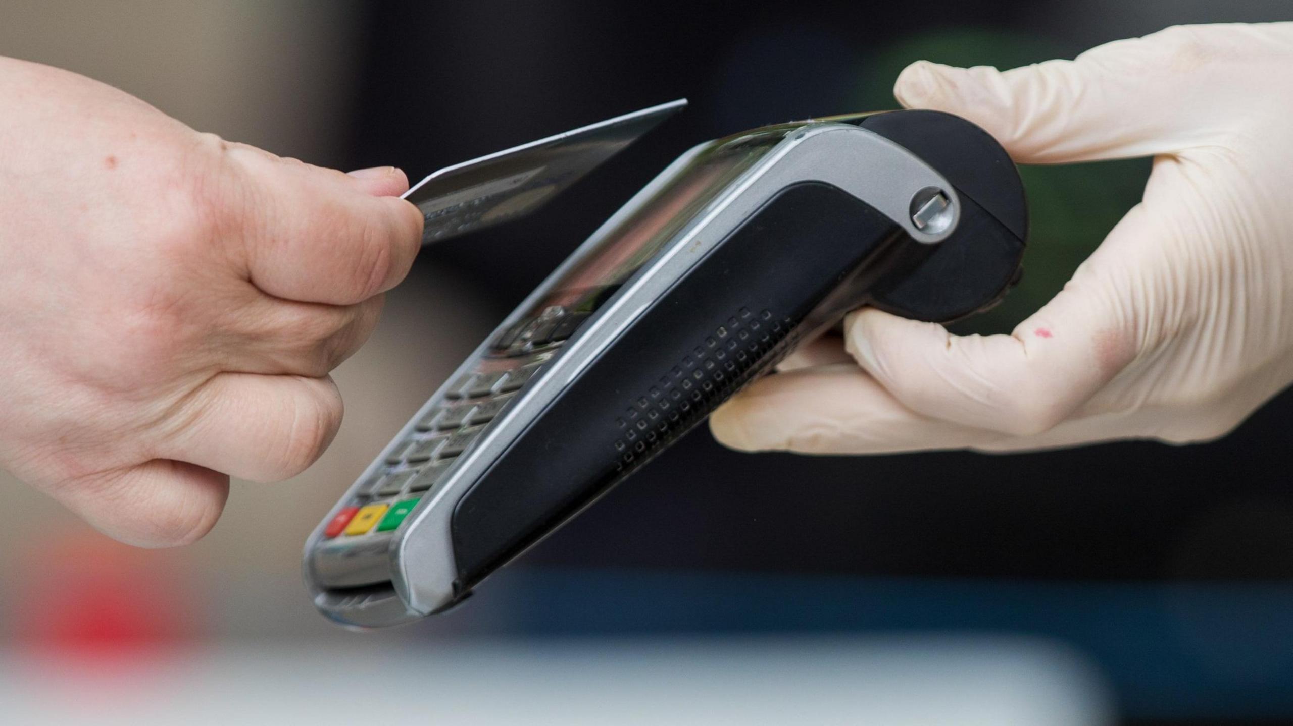 A person tapping their bank card on a card reader.