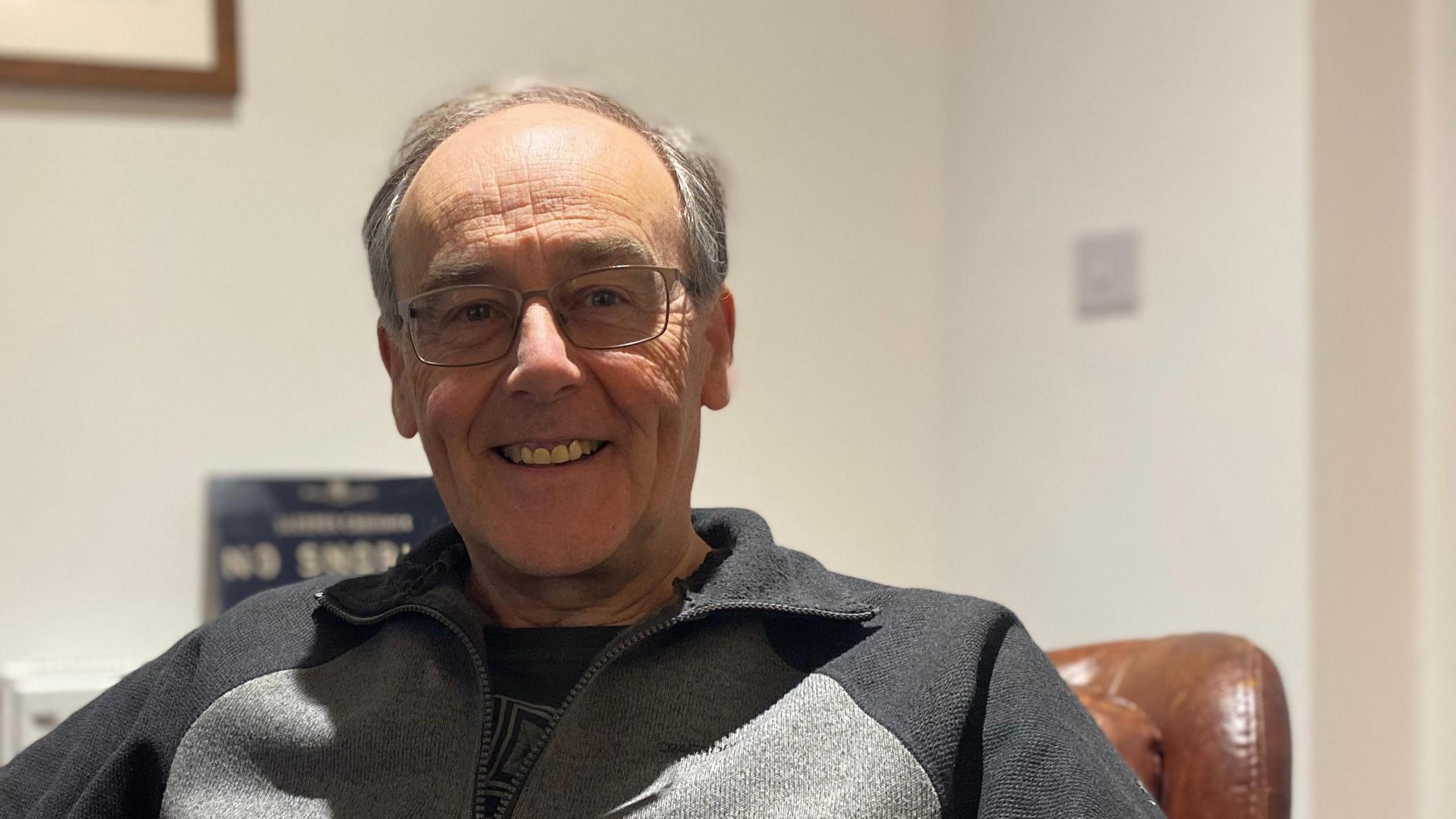 A bespectacled man sat in a leather chair