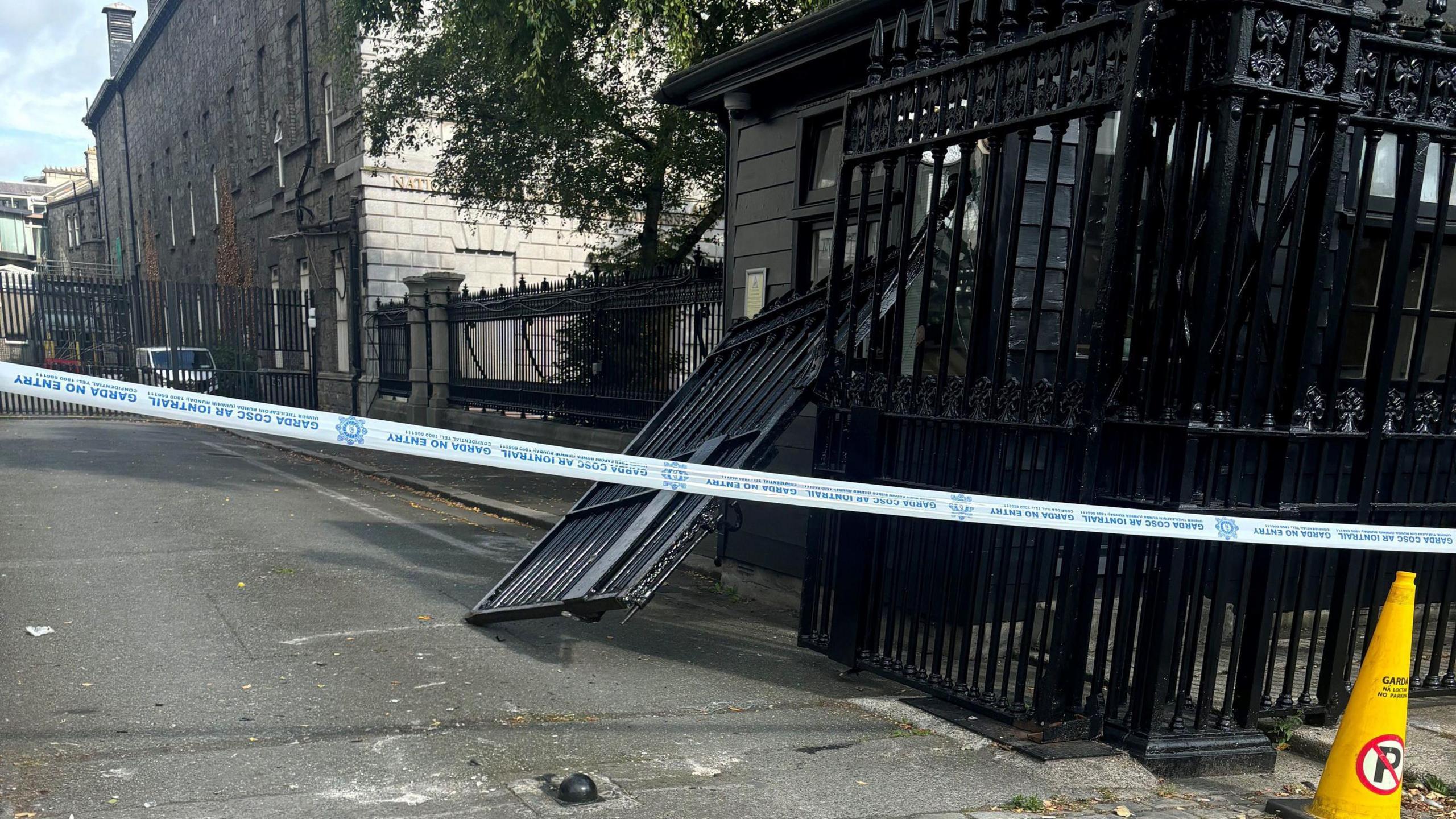 Damage caused to gates outside Government Buildings in Merrion Street, Dublin, after they were struck by a van. There is police tape in front of a broken gate.