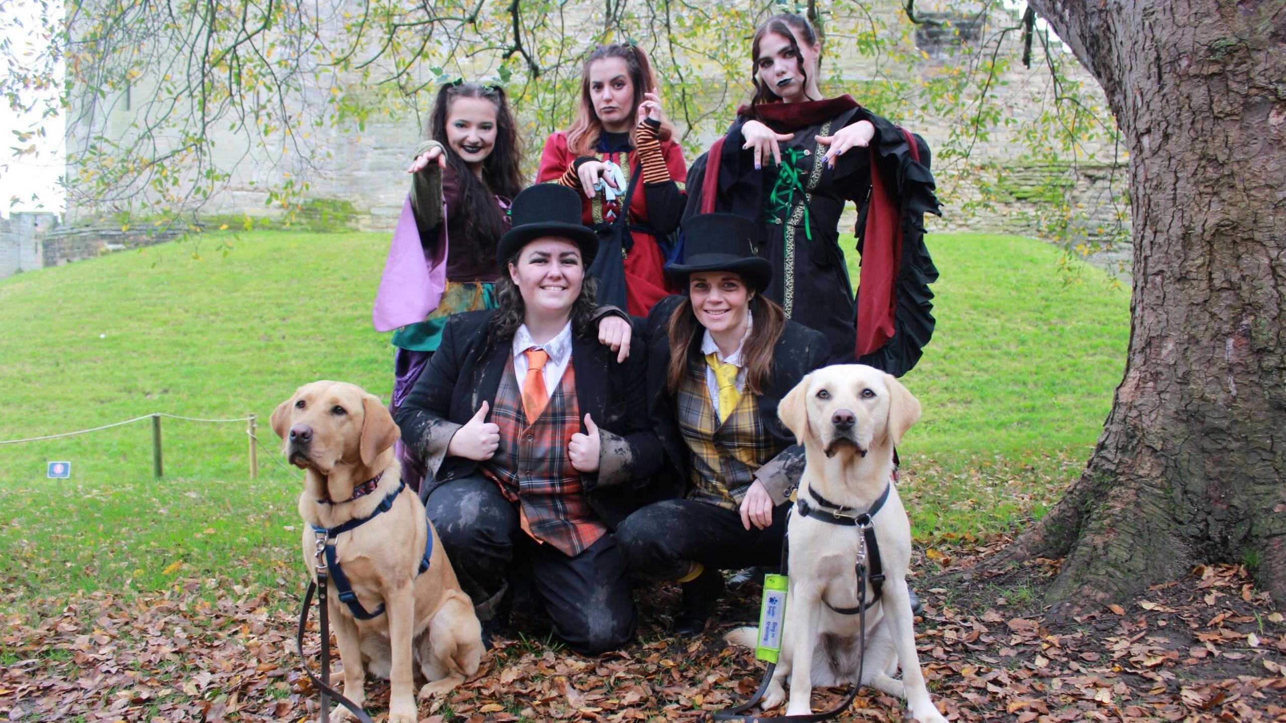 Two Labradors with five Halloween characters dressed in torn black suits and colourful adornments 