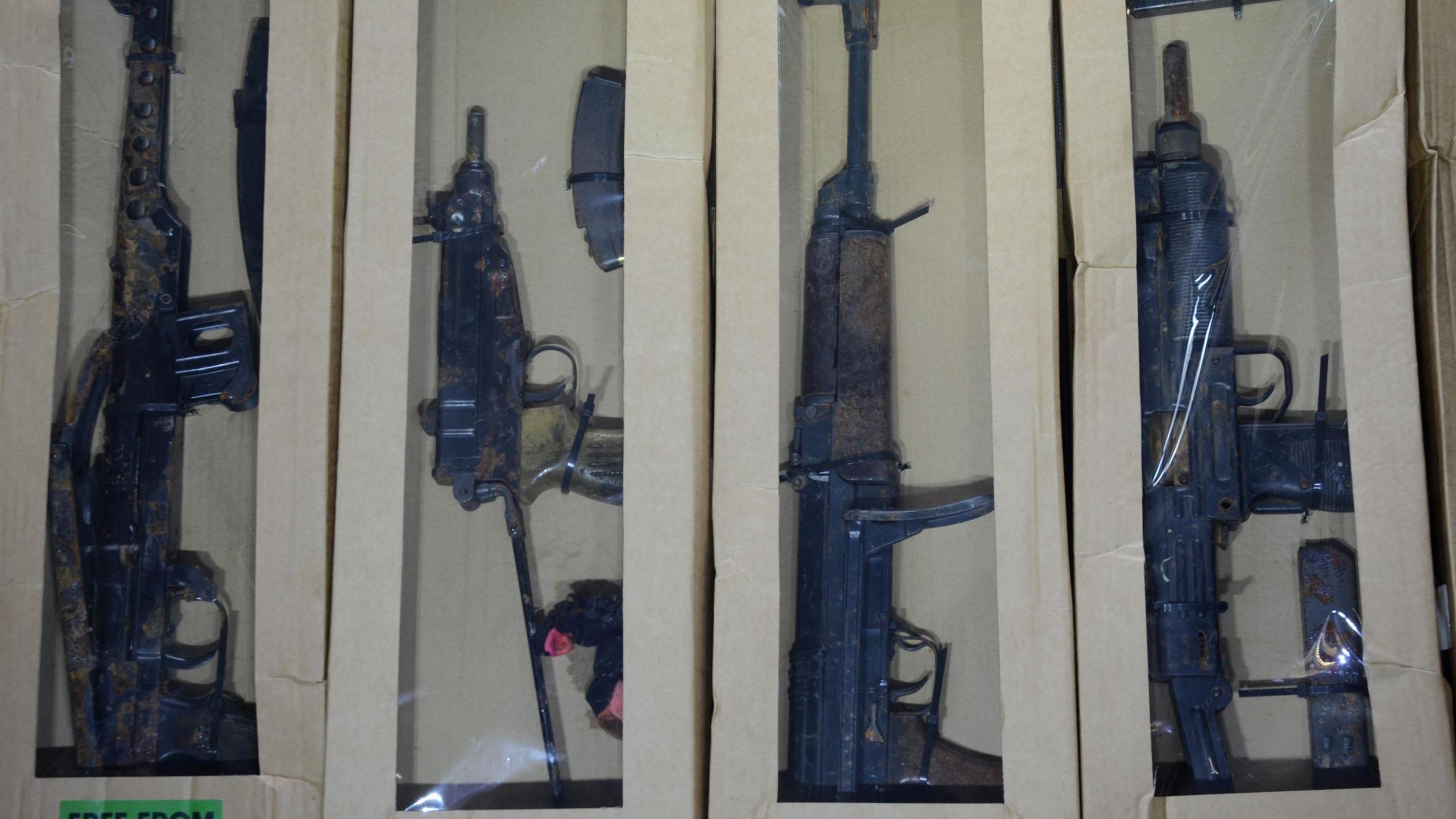 A picture of four guns in boxes. 