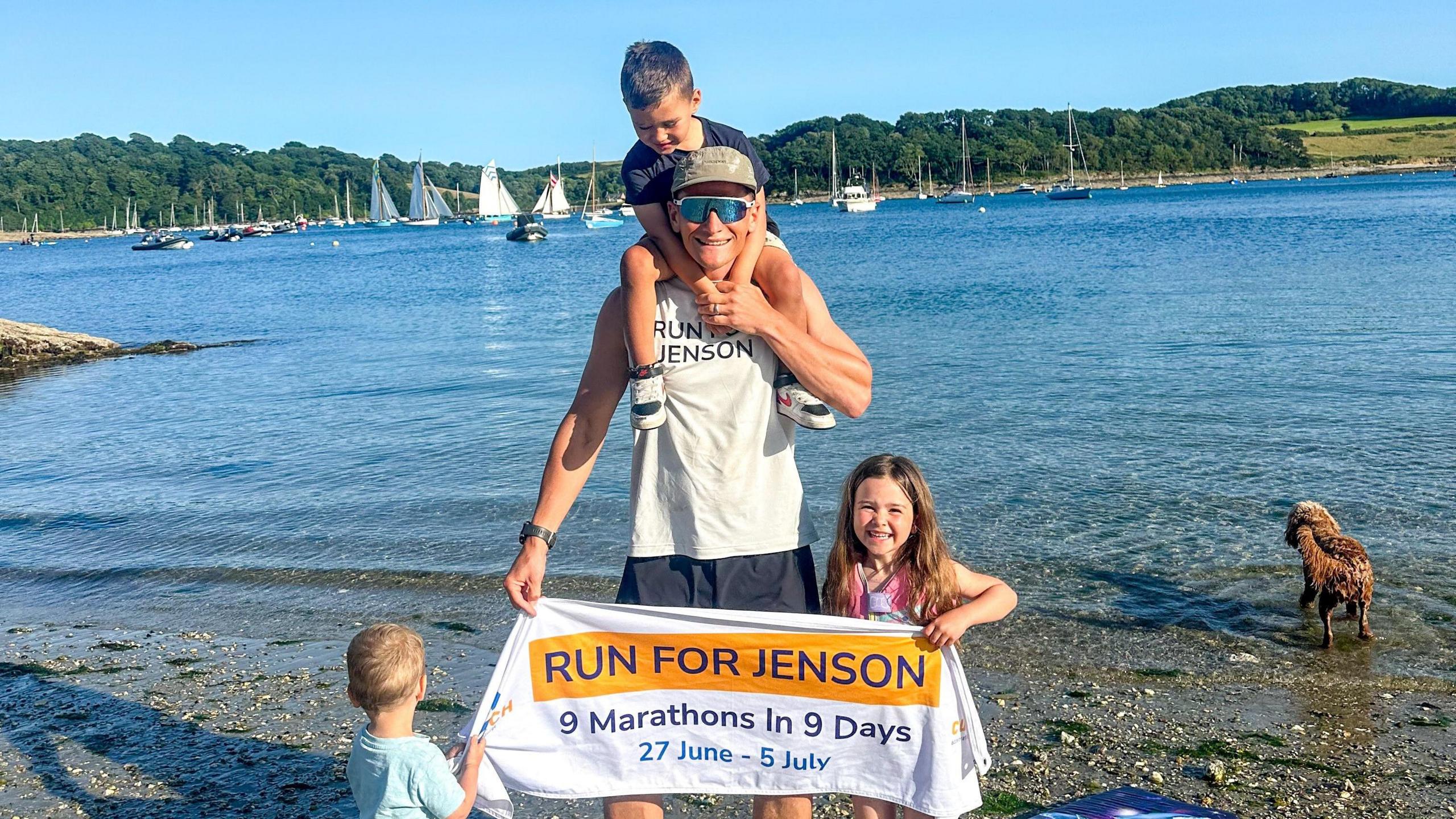 Tom and his children on a beach with a banner reading "Run for Jenson"