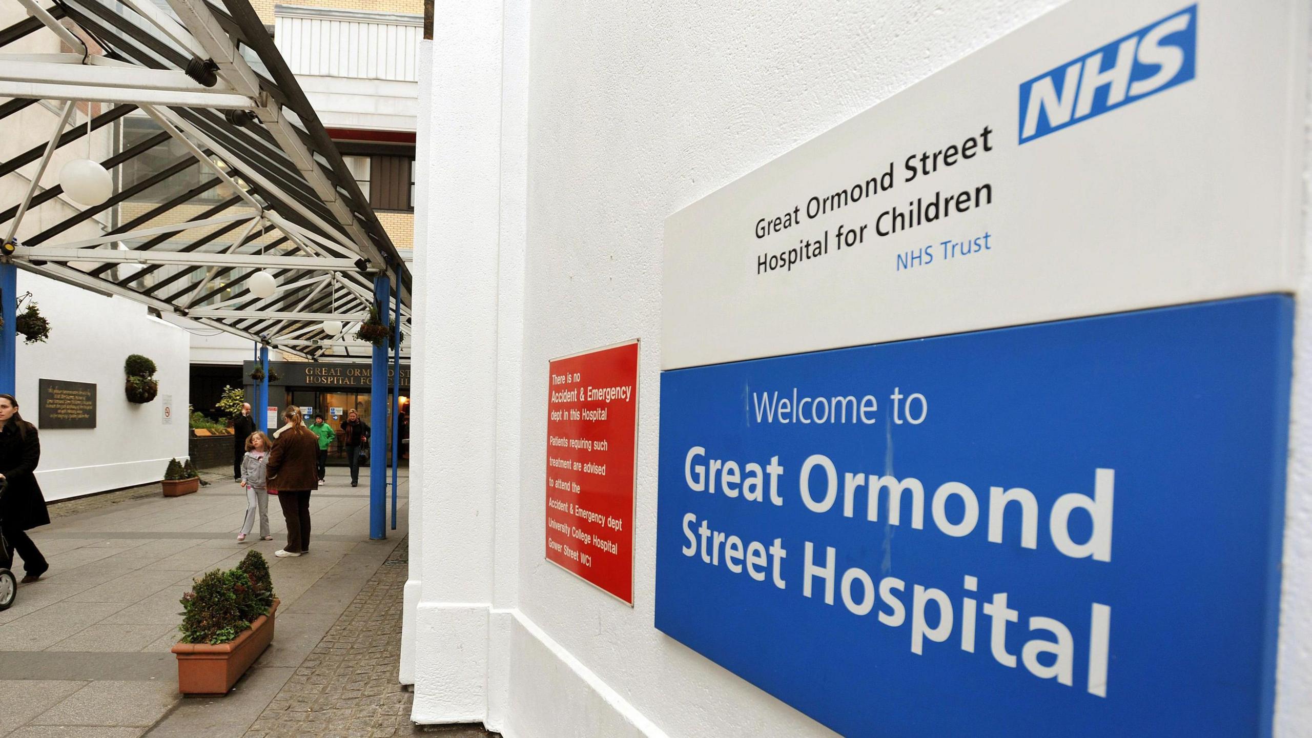 Sign of Great Ormond Street Hospital against a white wall with the NHS branding on the sign.