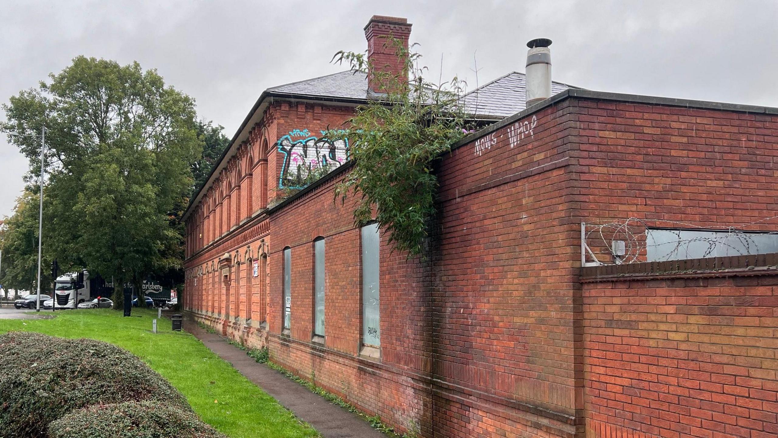 Side profile of former Northampton Gas Works building shown with boarded up windows and graffiti