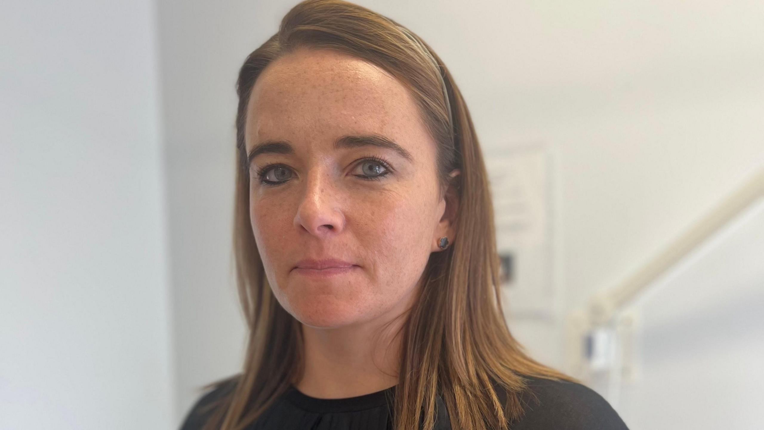 Dr Kate Corrigan, she is wearing a black top and has brown hair.